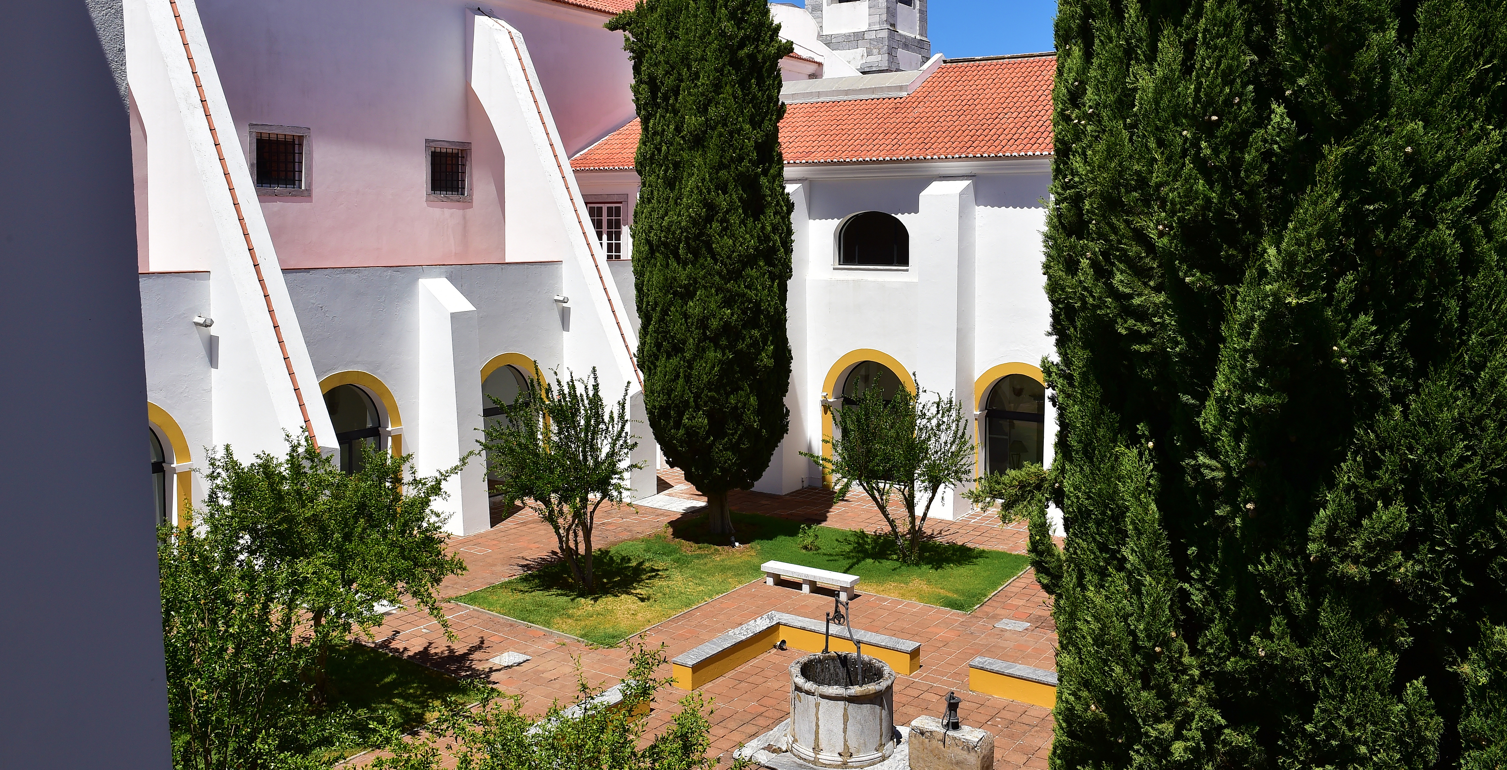 Innenhof zwischen den Klöstern der Pousada Convento Beja mit verschiedenen Bäumen und einem Brunnen