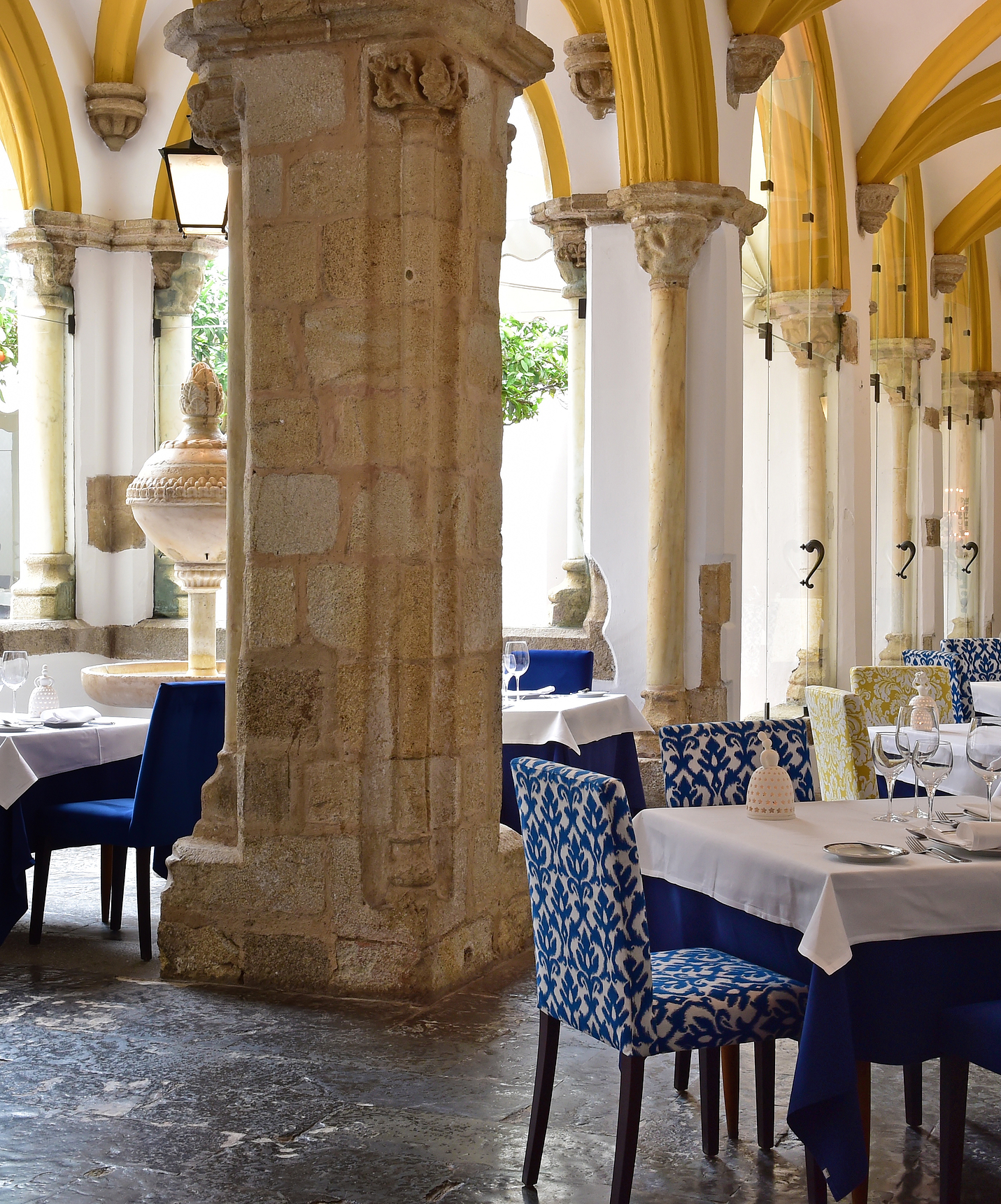 Hotelrestaurant mit Pool in Évora, Alentejo, in einem Kreuzgang mit einem langen schmalen Korridor und verzierten Steinbögen