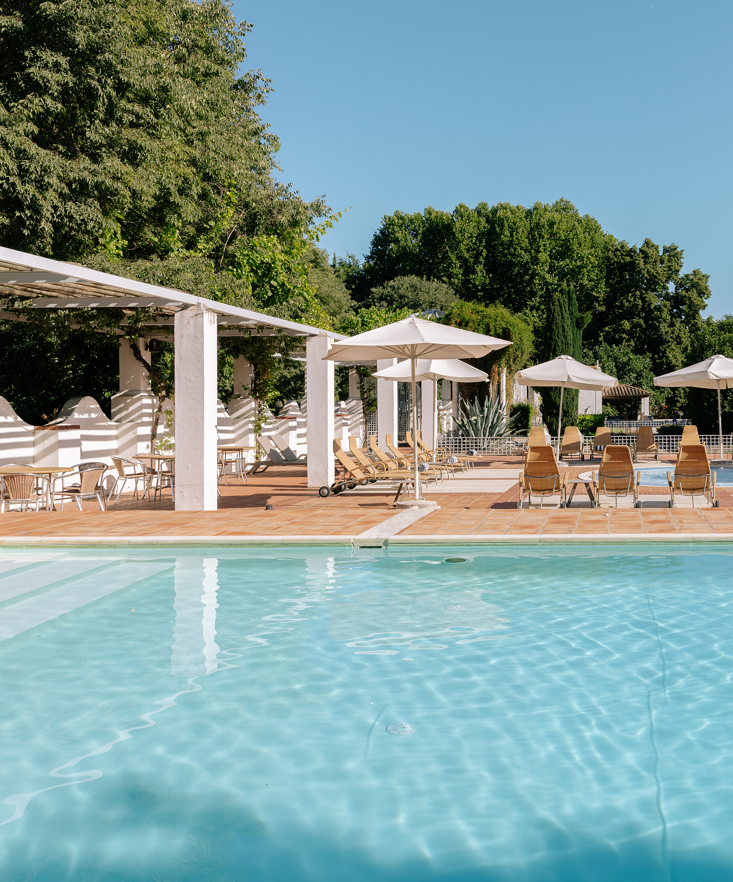 Außenpool in der Pousada Convento Vila Viçosa, mit mehreren Liegestühlen, Sonnenschirmen und Gartentischen