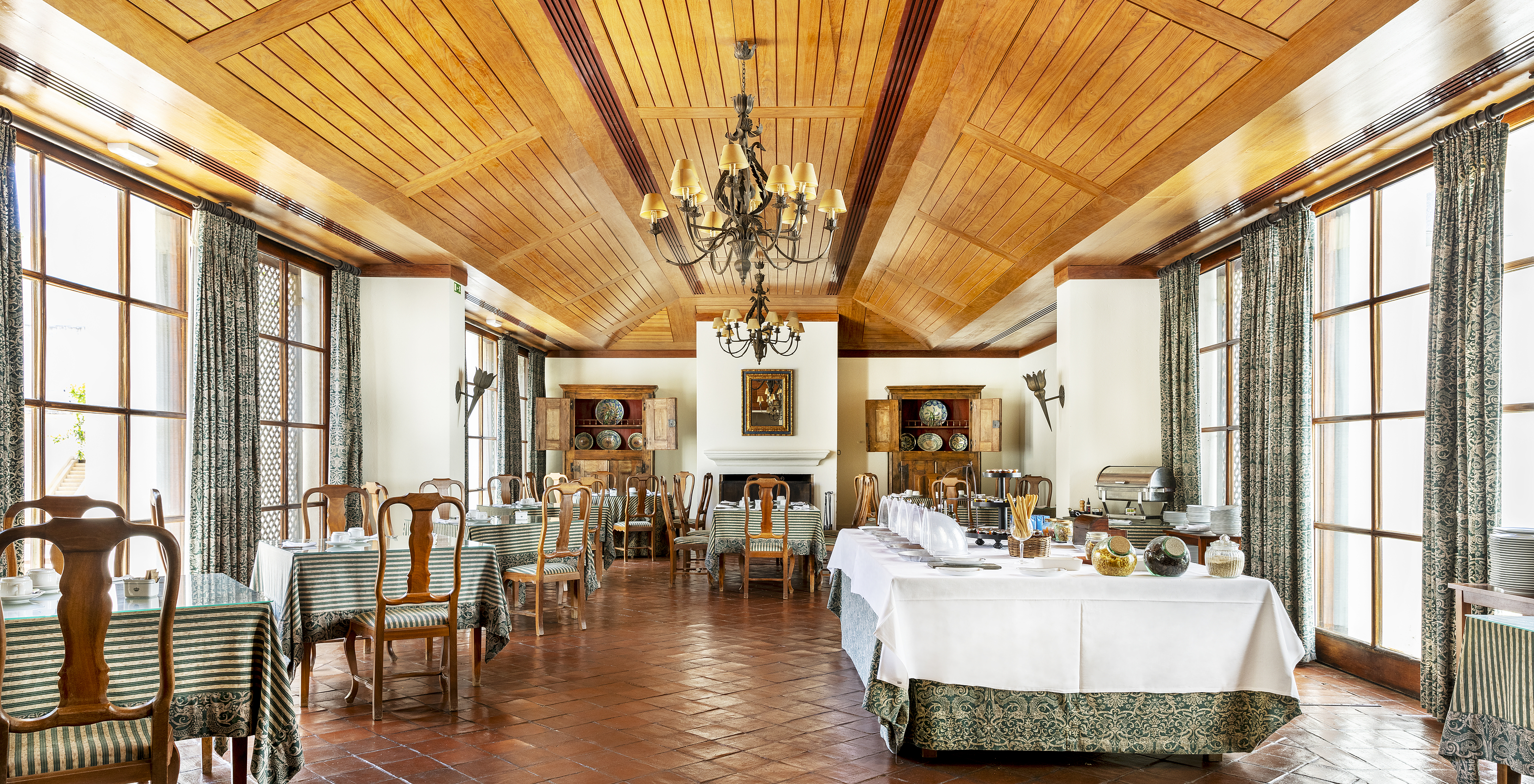 Das Restaurant D Carlos, im historischen Hotel in Vila Viçosa, hat einen Raum mit Tischen, Stühlen und Holzdecke