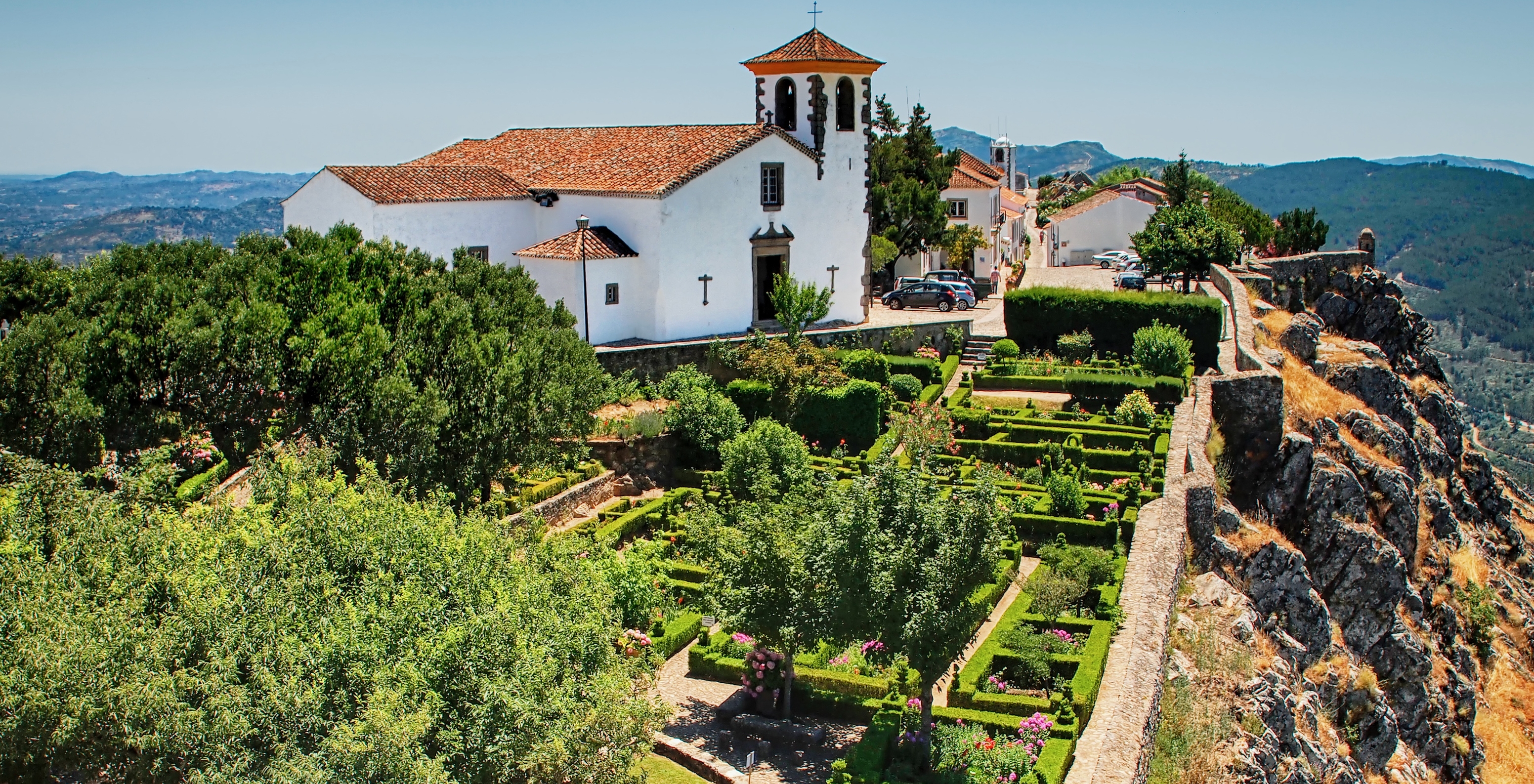 Luftaufnahme einer Kirche neben der Pousada Marvão, umgeben von Vegetation auf einem Hügel