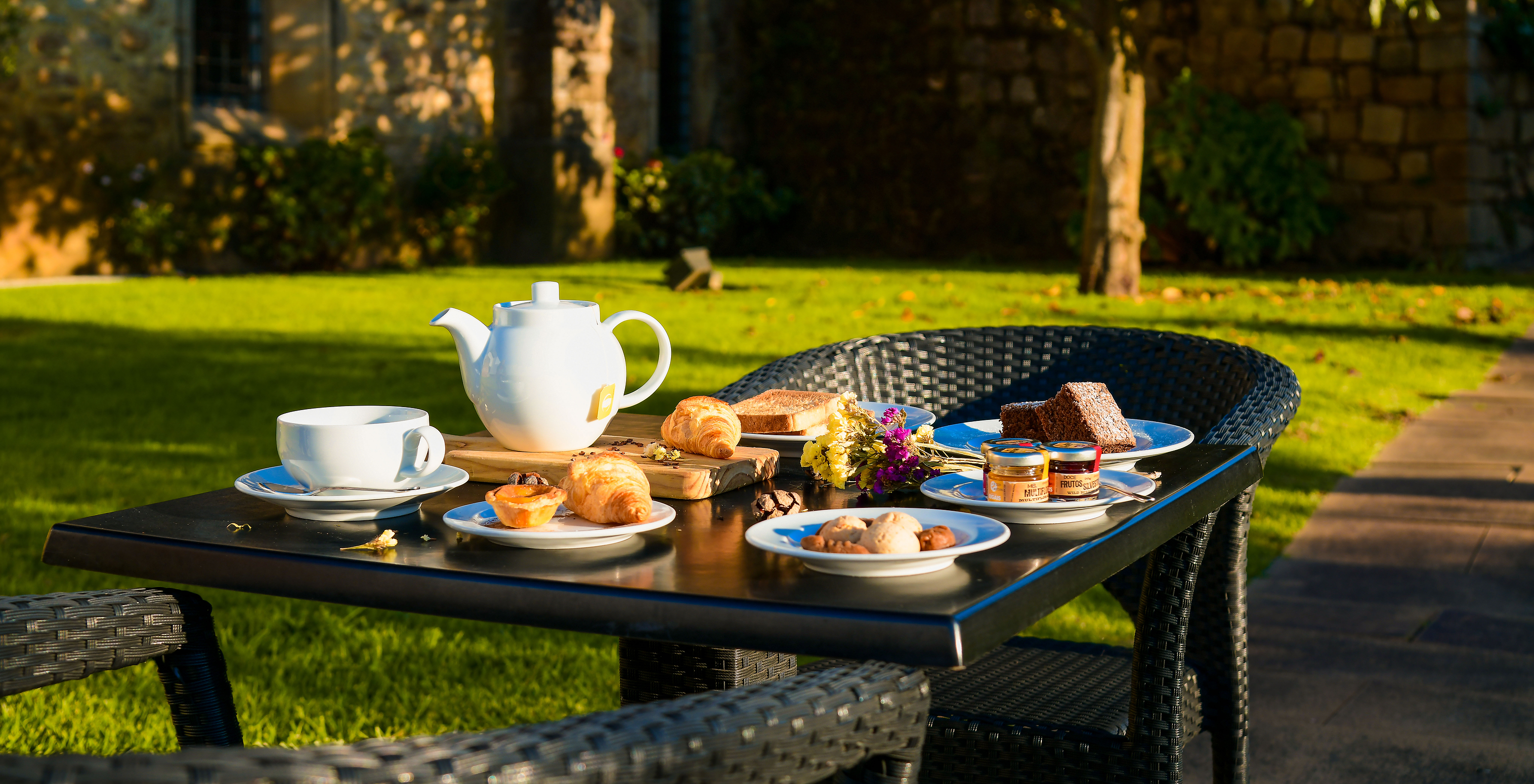 Frühstückstisch mit einer Auswahl an Gebäck und Süßigkeiten im Freien im Hotelgarten