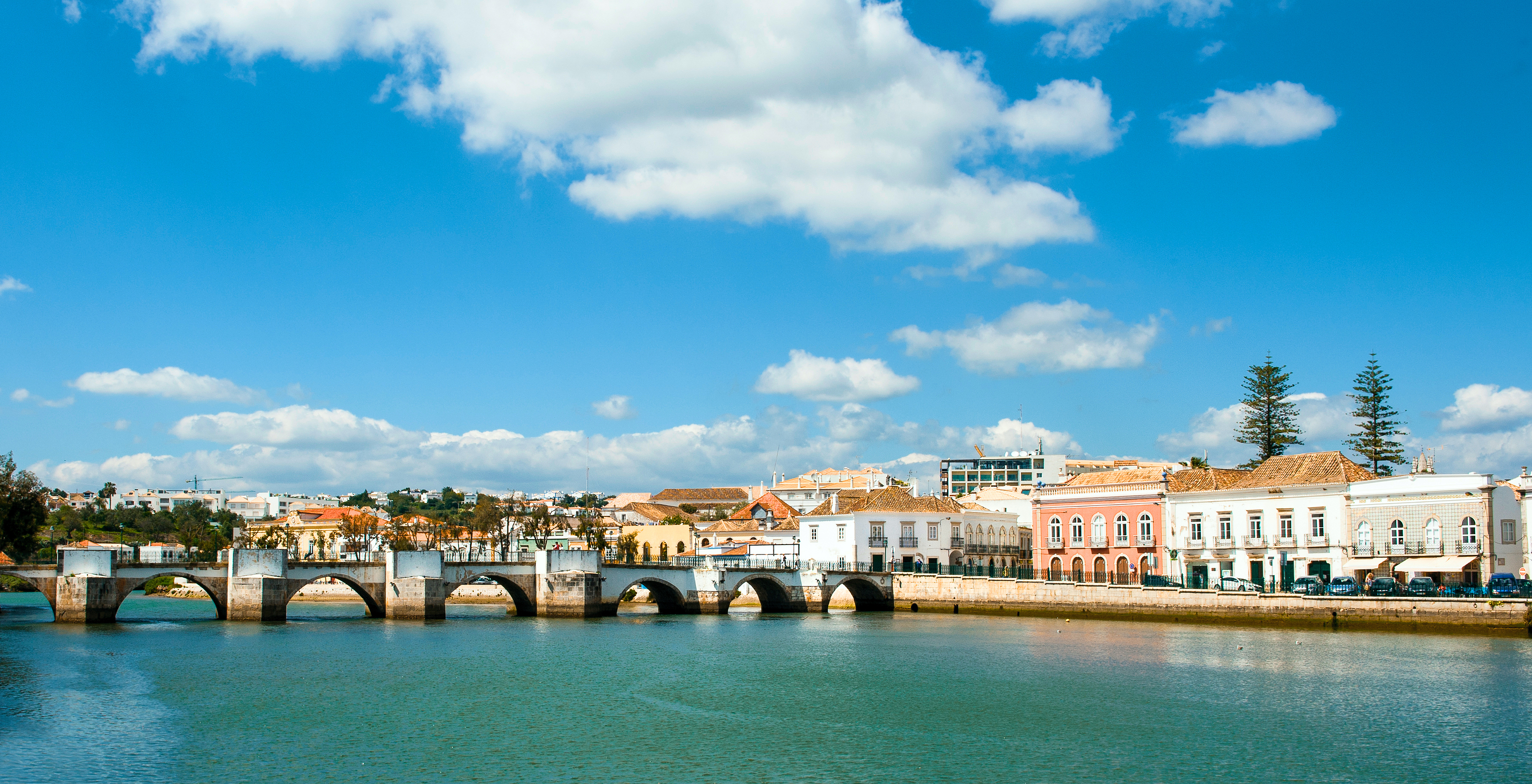 Typischer Blick auf Tavira mit römischer Brücke über den Fluss Gilão an einem sonnigen Tag