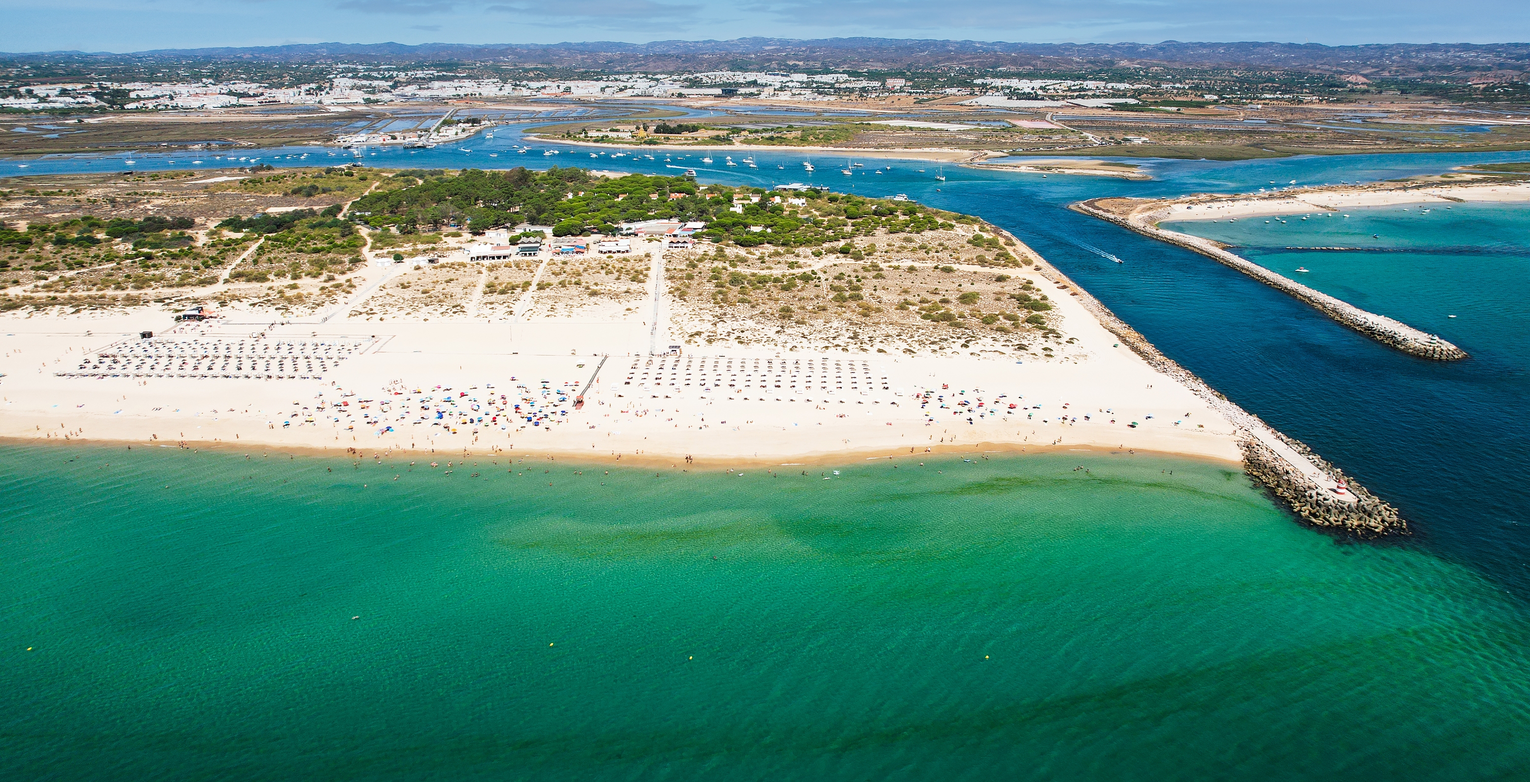 Strand auf der Insel Tavira mit einem langen Streifen aus hellem Sand und kristallklarem Wasser in Türkis