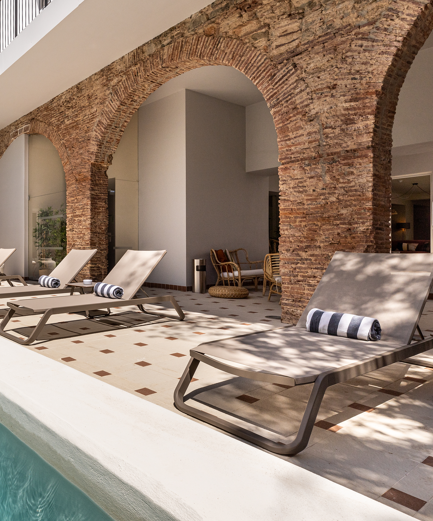 Außenpool im Patio mit Ziegelbögen, Liegen und Handtüchern im historischen Hotel in der Nähe des Strandes