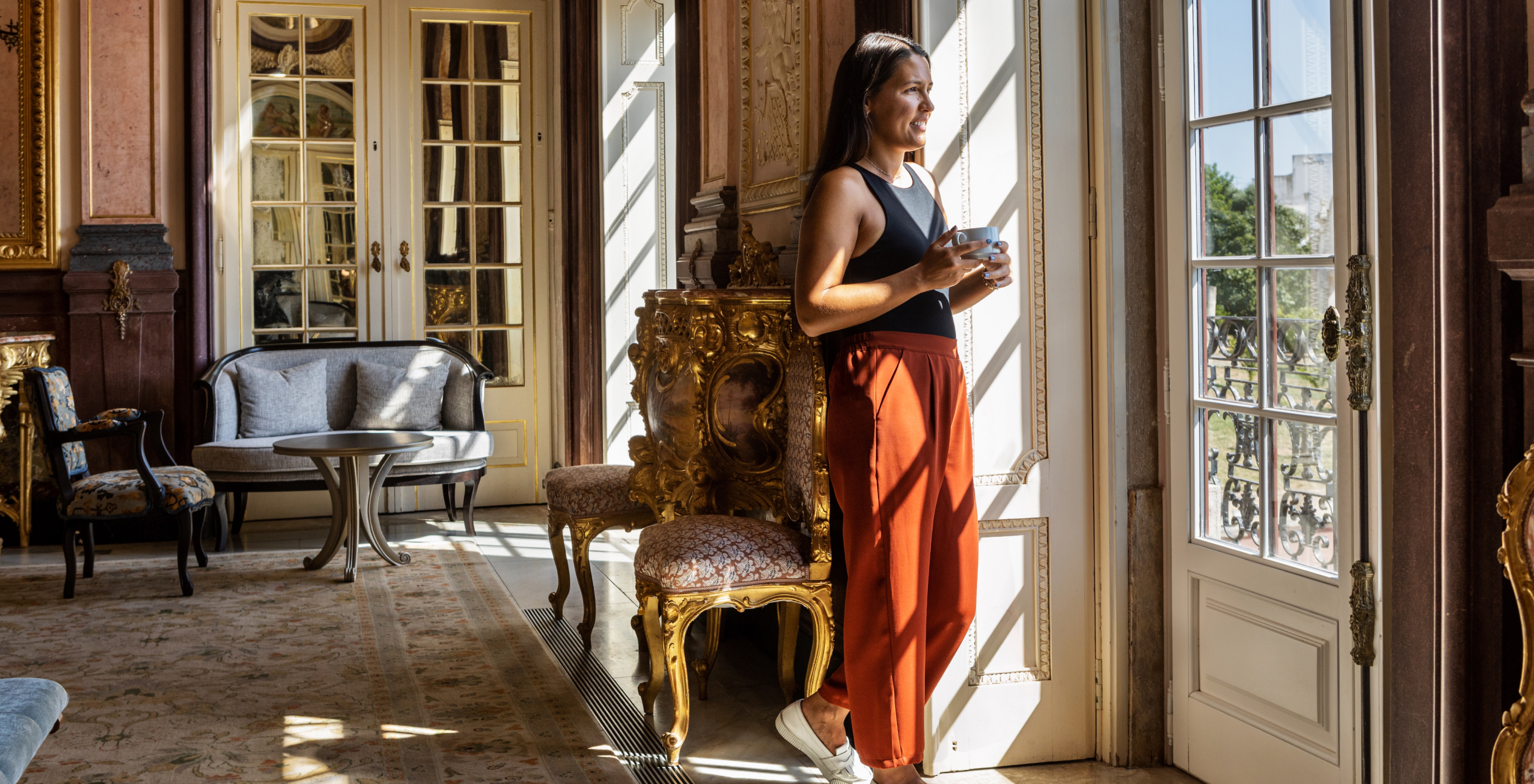 Mädchen schaut aus einem luxuriösen Fenster der Pousada Palácio Estoi, historisches Hotel in der Algarve mit Pool