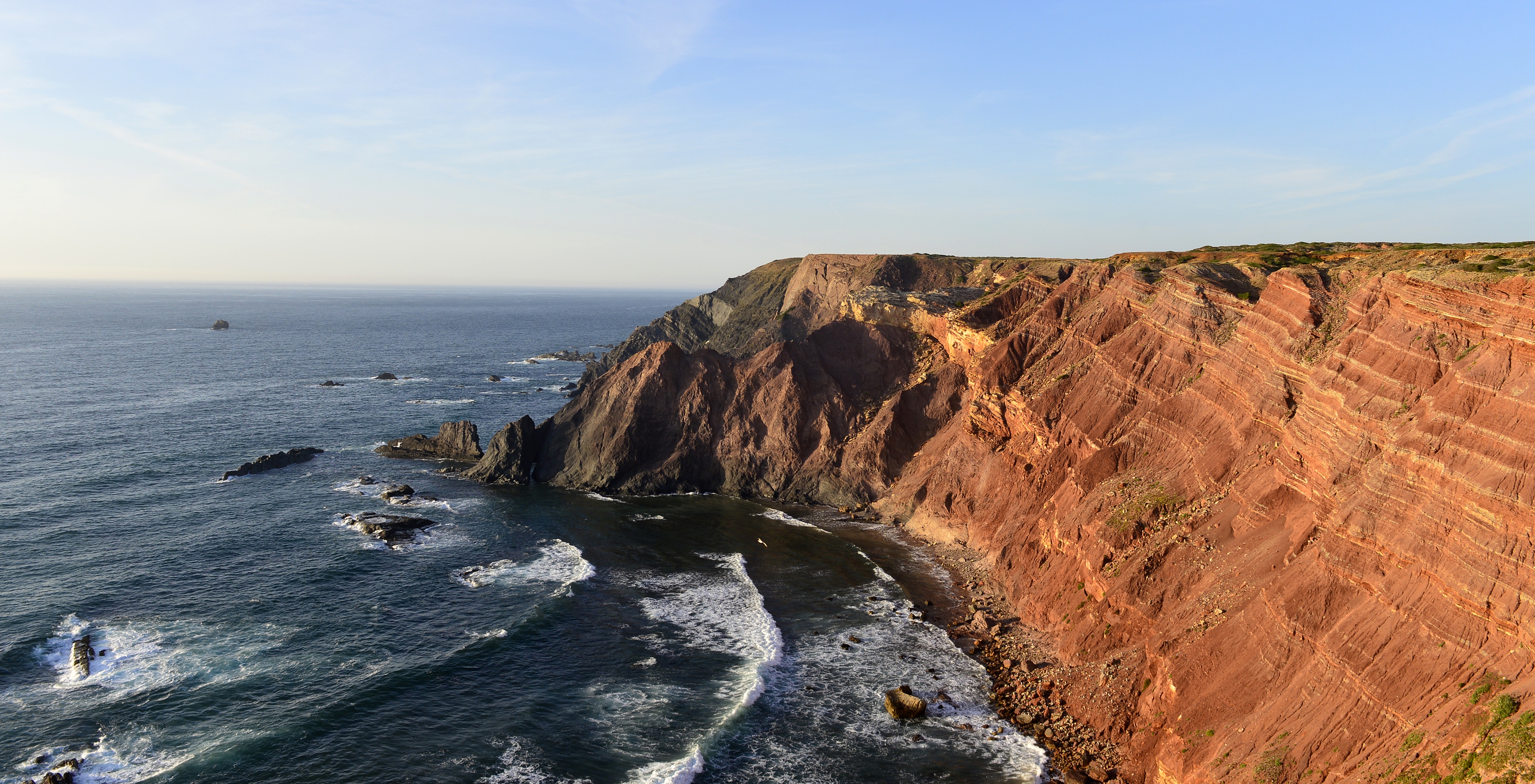 Blick auf eine Klippe mit roten Tönen neben der Pousada Sagres, vor dem Meer