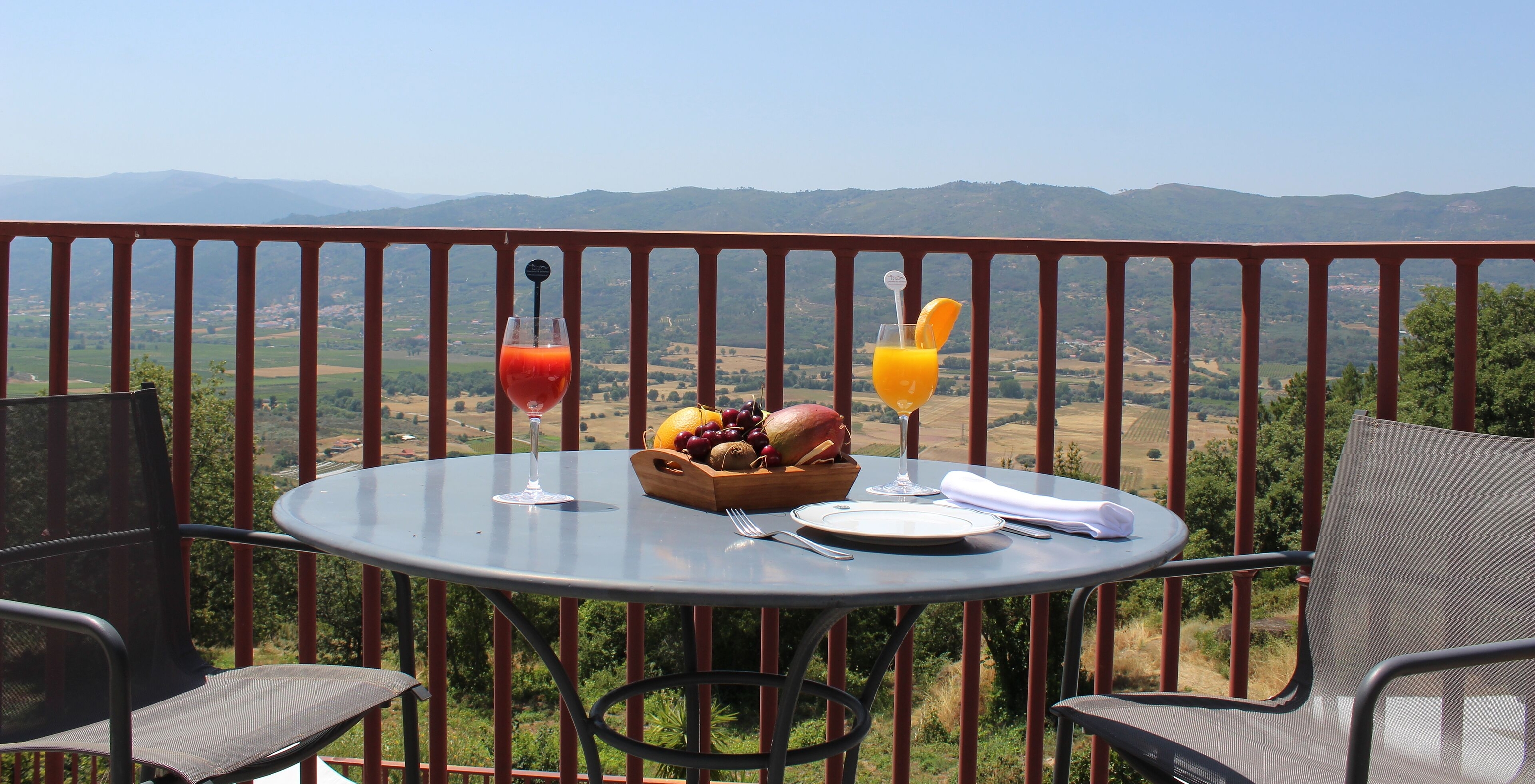 Das Twin Zimmer mit Balkon der Pousada Convento Belmonte hat einen Tisch mit zwei Säften und einer beeindruckenden Aussicht