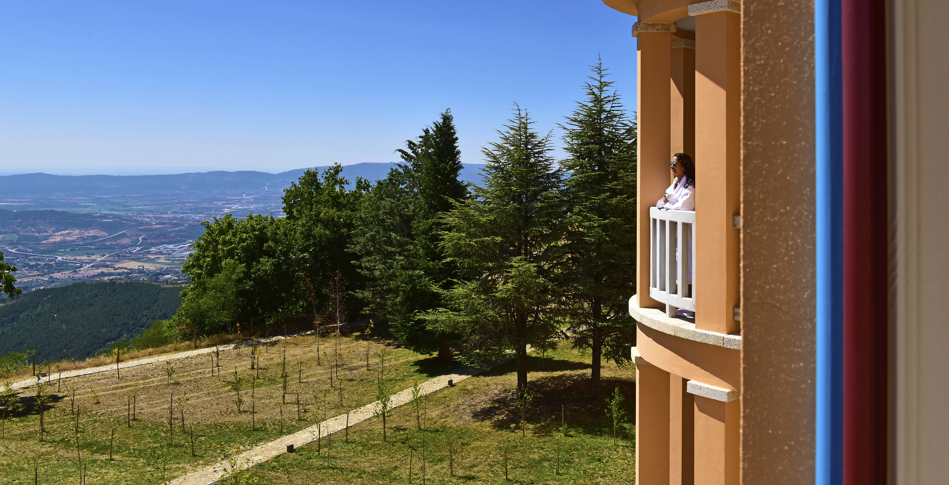 Person im Bademantel, die von ihrem Balkon in der Pousada Serra da Estrela schaut