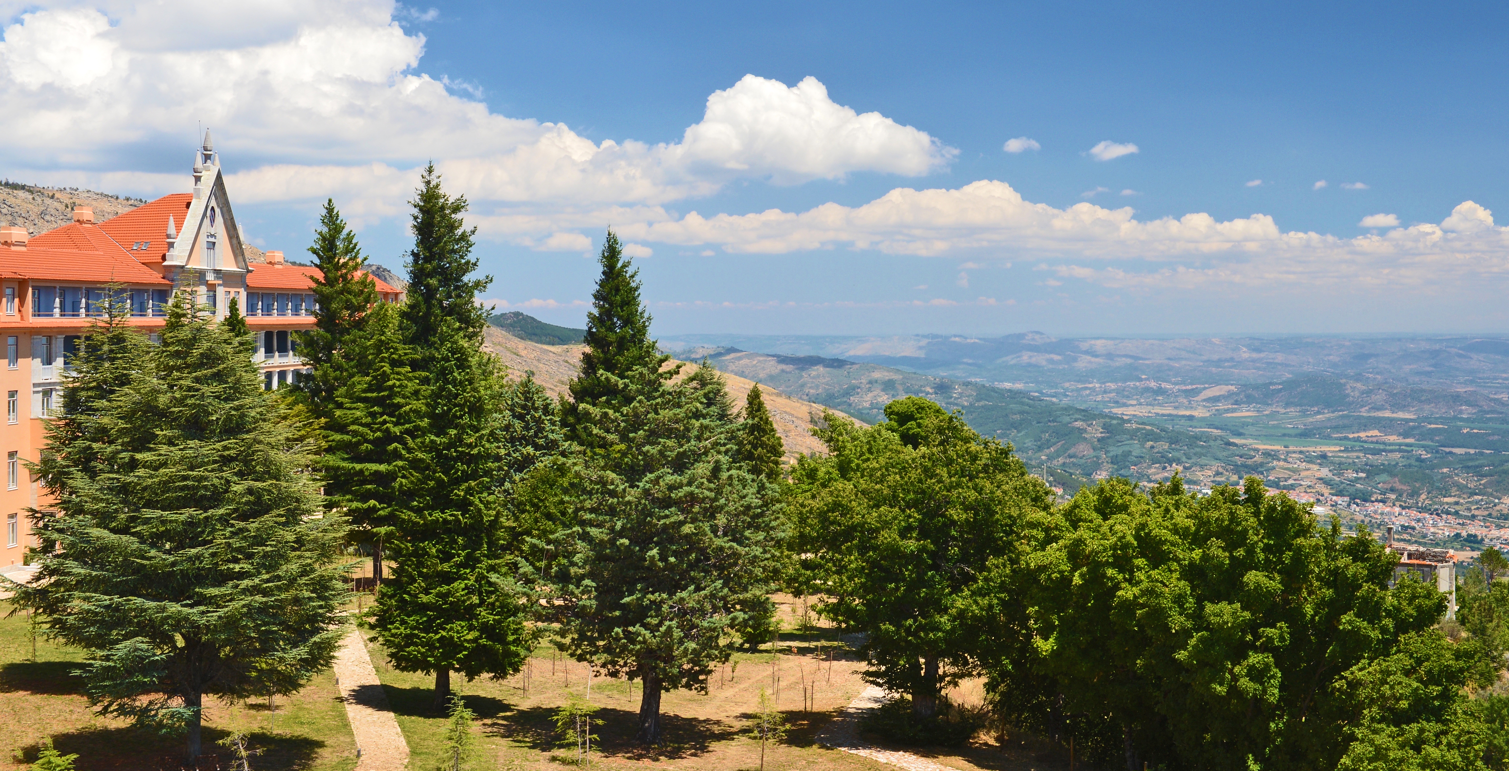 Blick auf die Serra da Estrela mit Kiefern, die sich gegen den blauen Himmel mit weißen Wolken abheben