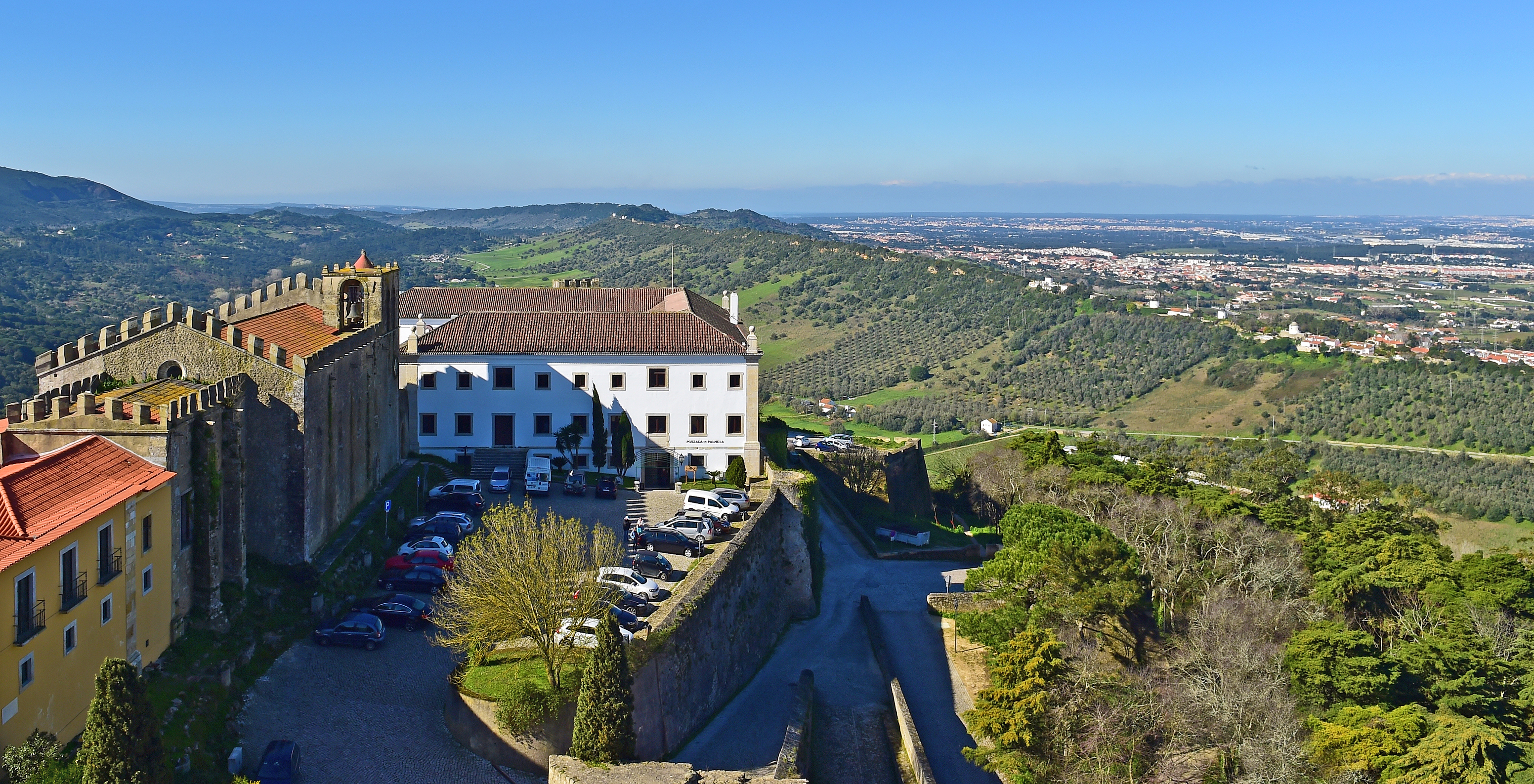 Parkplatz mit mehreren Autos und Bergen im Hintergrund an der Pousada Castelo Palmela, Hotel in Palmela