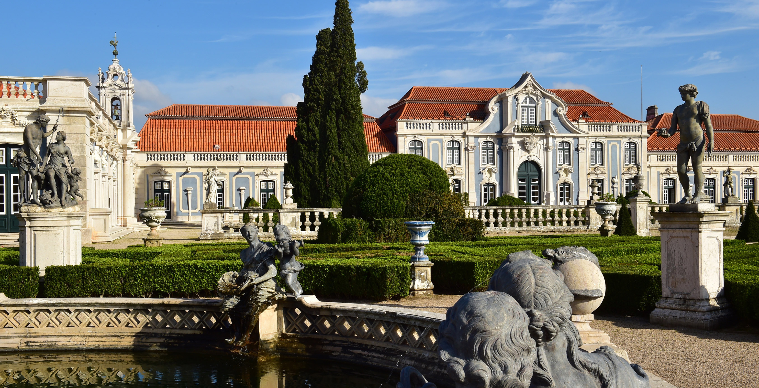 Außenansicht des Nationalpalasts von Queluz mit Brunnen, Gärten und mehreren dekorativen Statuen