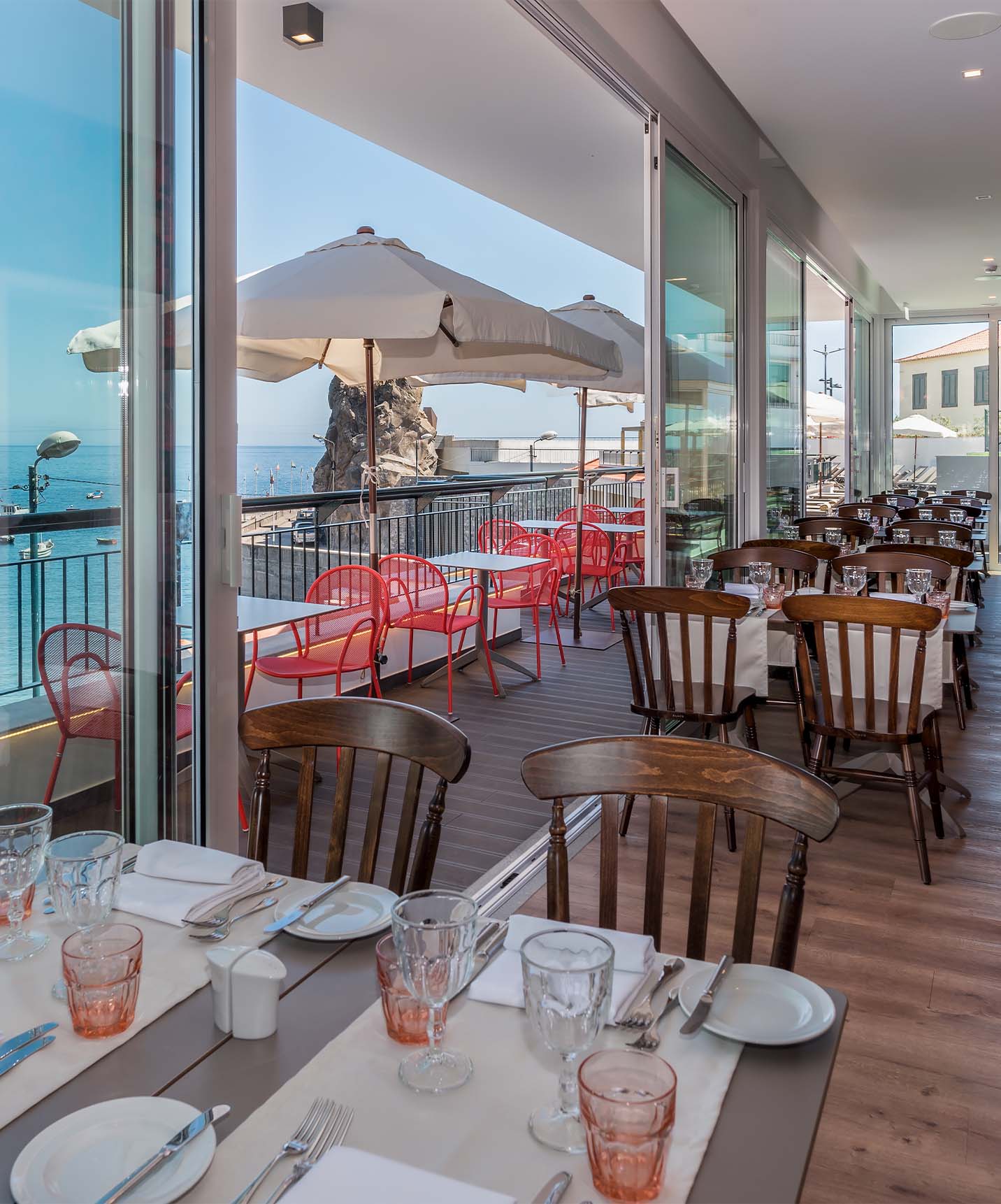 Das Hotel in der Bucht von Câmara de Lobos, nahe Funchal, hat ein Restaurant mit Tischen innen und außen mit Meerblick