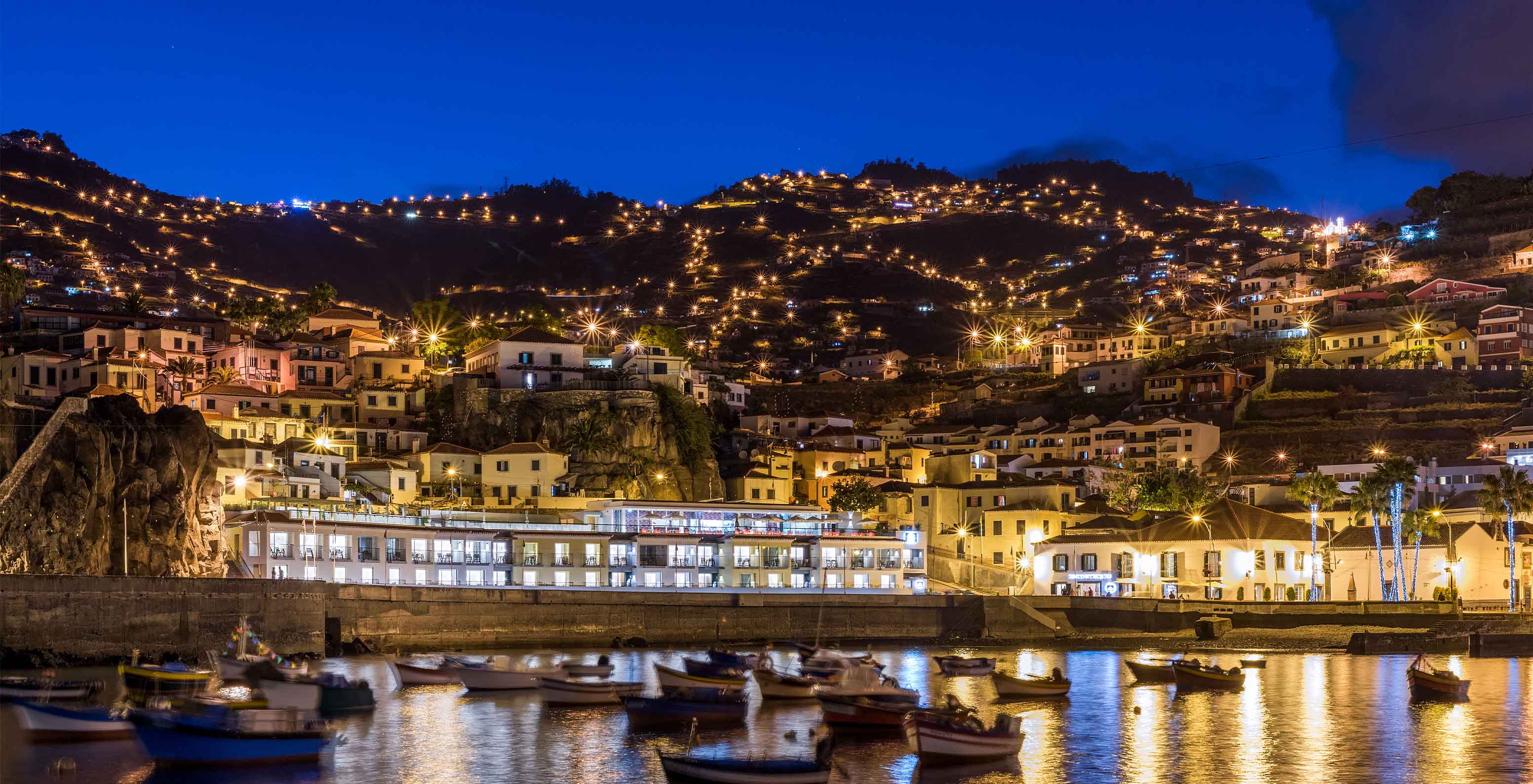 Panoramablick auf das Hotel in der Bucht von Câmara de Lobos, nahe Funchal, nachts mit bunten Gebäuden