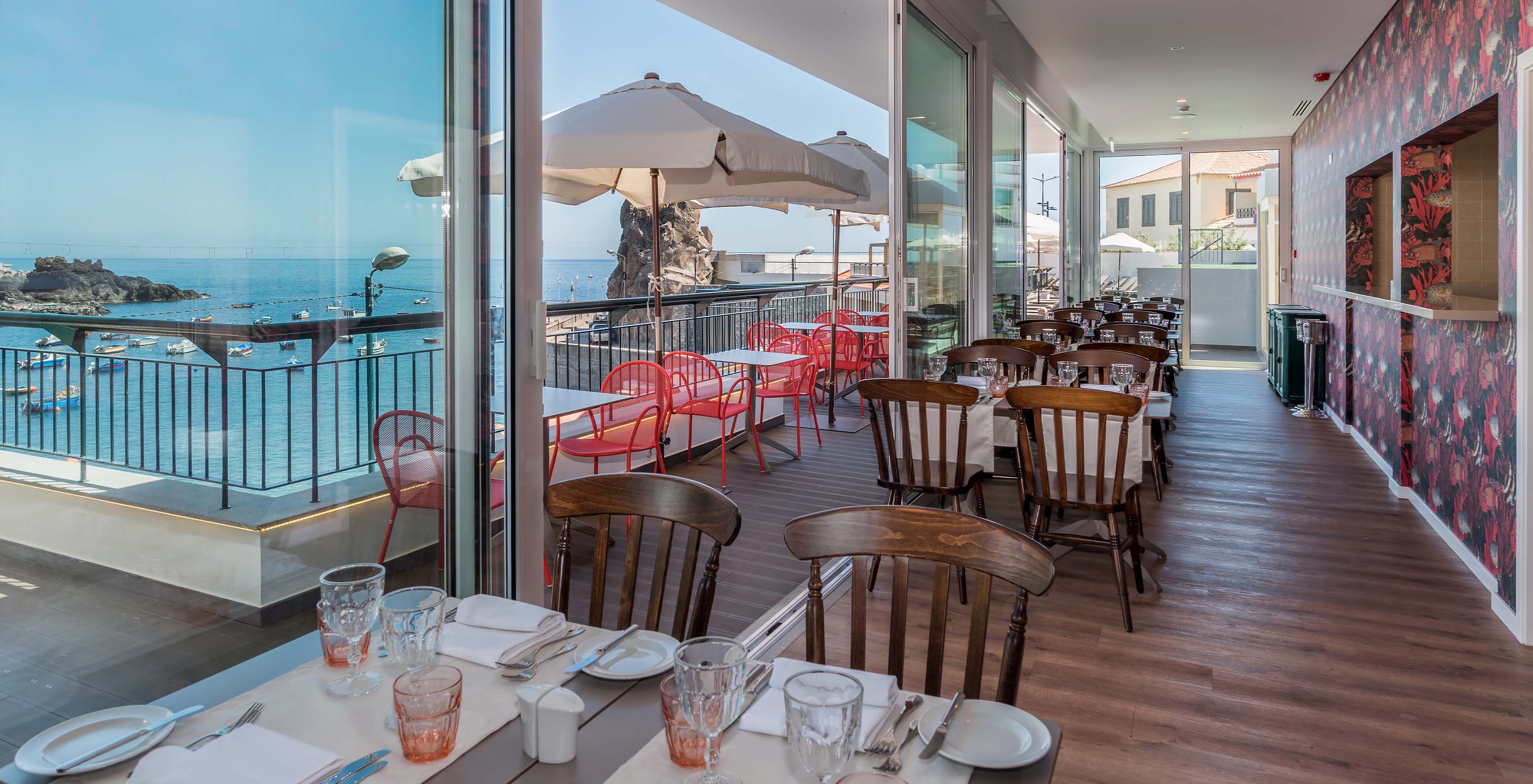 Das Hotel in der Bucht von Câmara de Lobos, nahe Funchal, hat ein Restaurant mit Tischen drinnen und draußen mit Meerblick