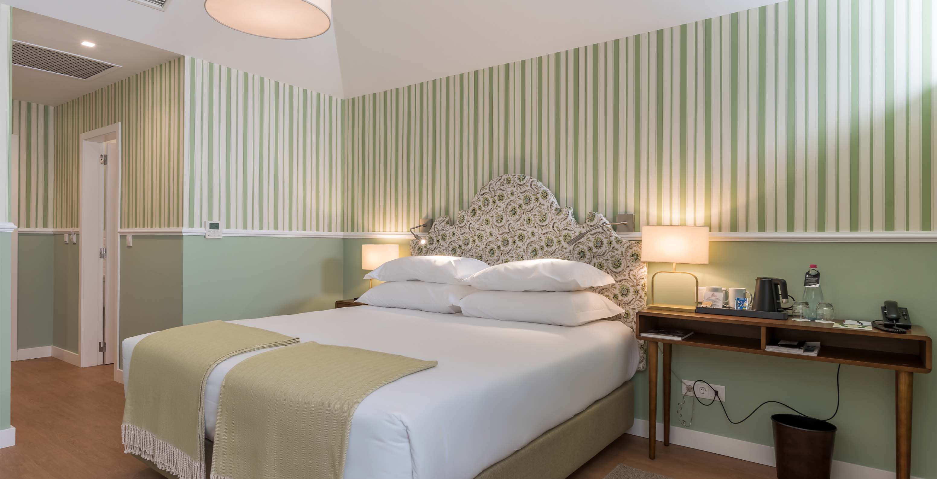 Das Classic Zimmer im Pestana Churchill Bay hat ein Doppelbett, gestreifte Tapete in Grüntönen und einen Tisch