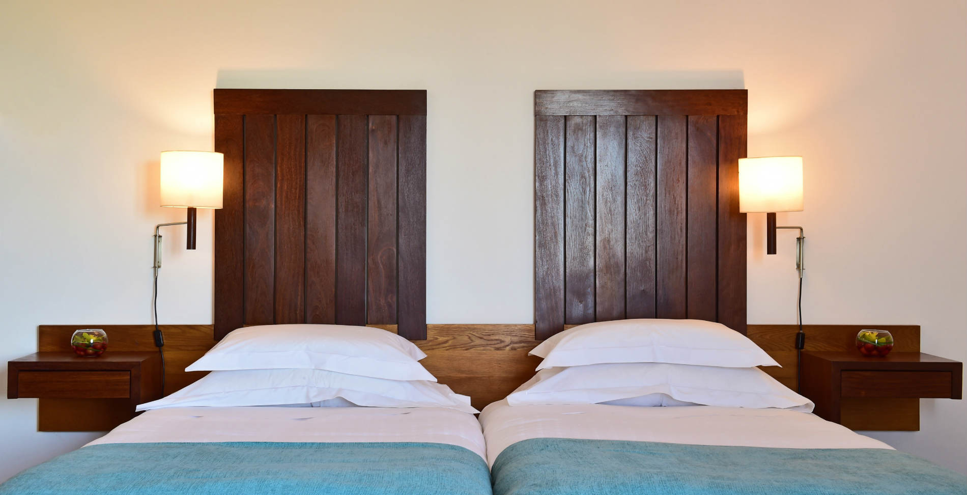 The Classic Family Room of the Pousada Castelo Alcácer do Sal has two beds, with a blue blanket and a wooden headboard