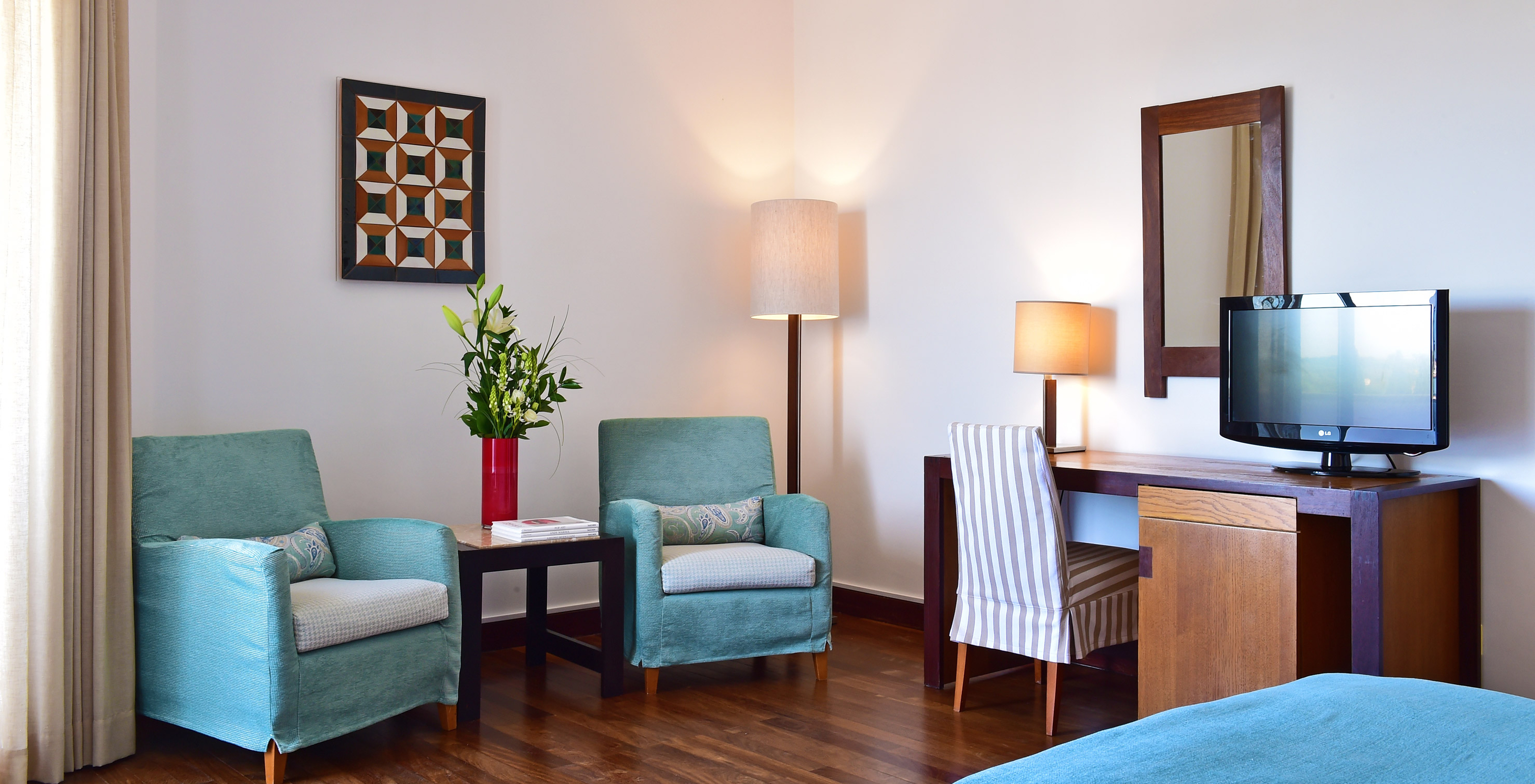 The Classic Family Room of the Pousada Castelo Alcácer do Sal has a desk with a television and two blue armchairs