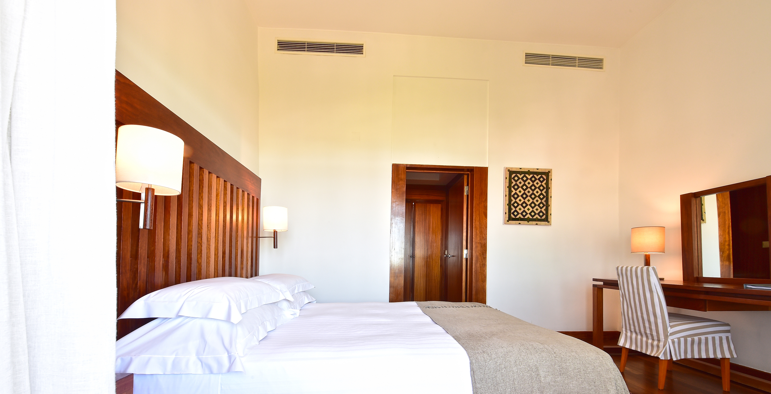 The Standard Suite of the Pousada Castelo Alcácer do Sal has a double bed with a beige blanket, and a desk