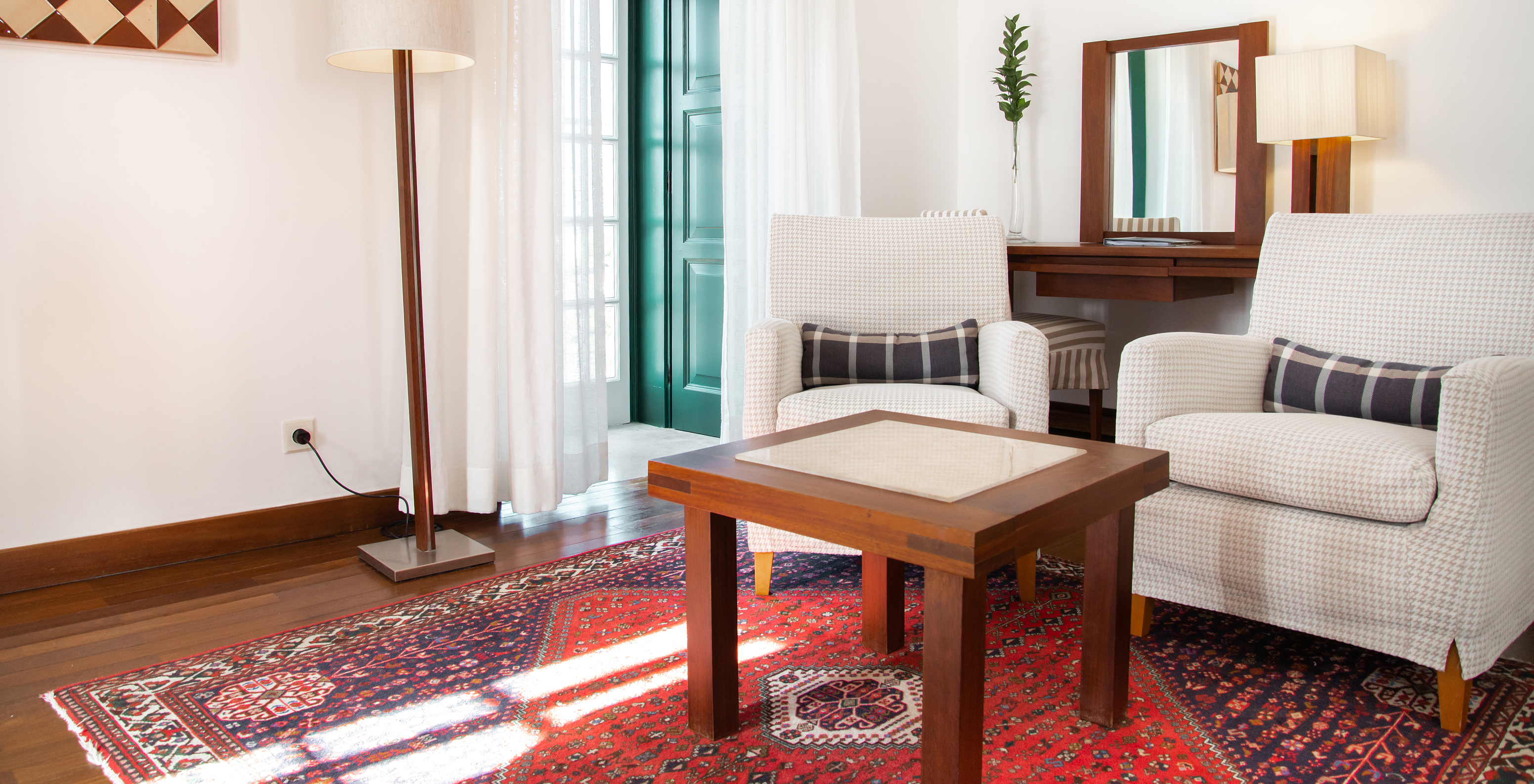 The Standard Suite of the Pousada Castelo Alcácer do Sal has a seating area with two armchairs and a table