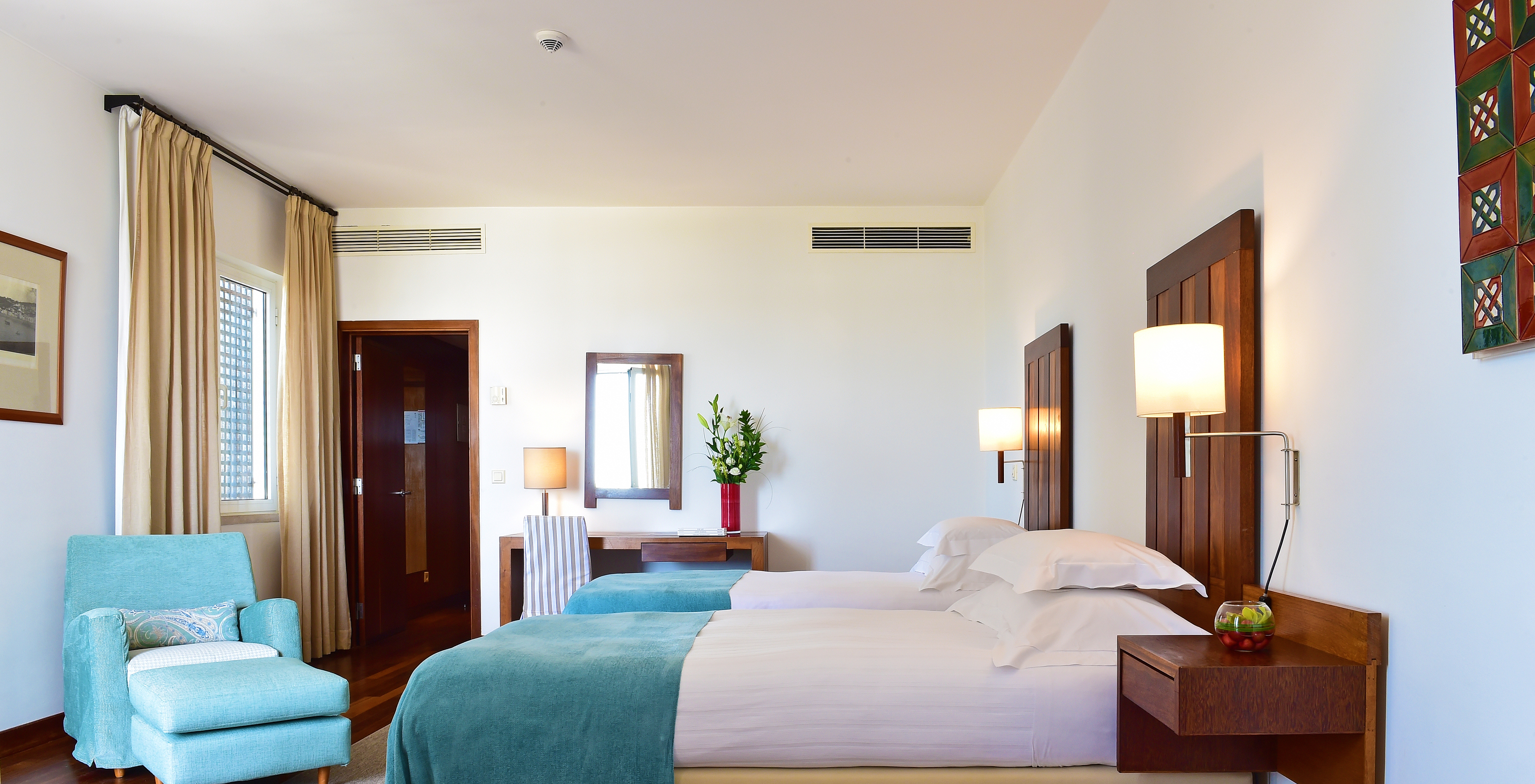 The Large Family Room of the Pousada Castelo Alcácer do Sal has two separate beds, with a blue blanket and an armchair