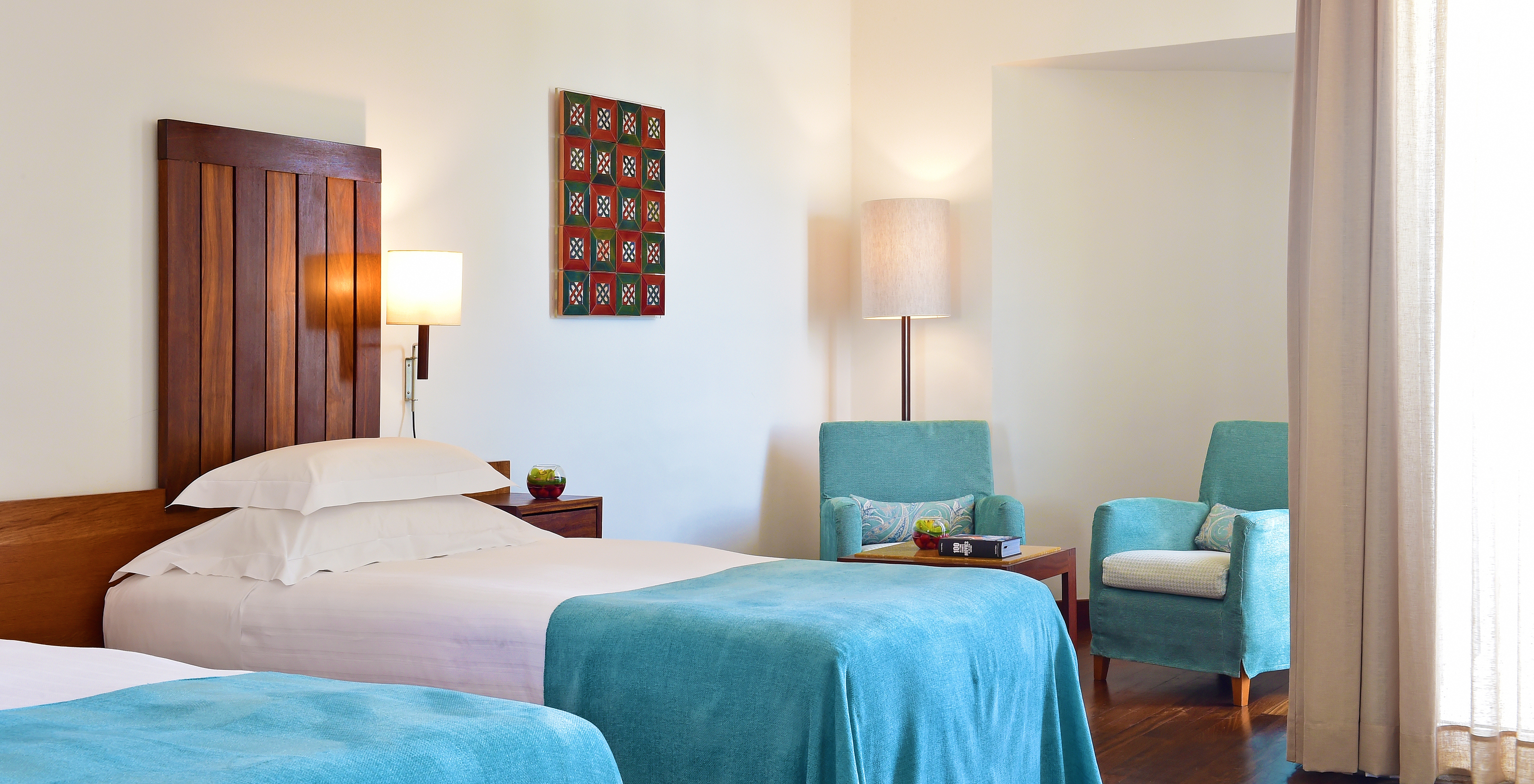 The Superior Room of the Pousada Castelo Alcácer do Sal has two separate beds, with a blue blanket and two armchairs