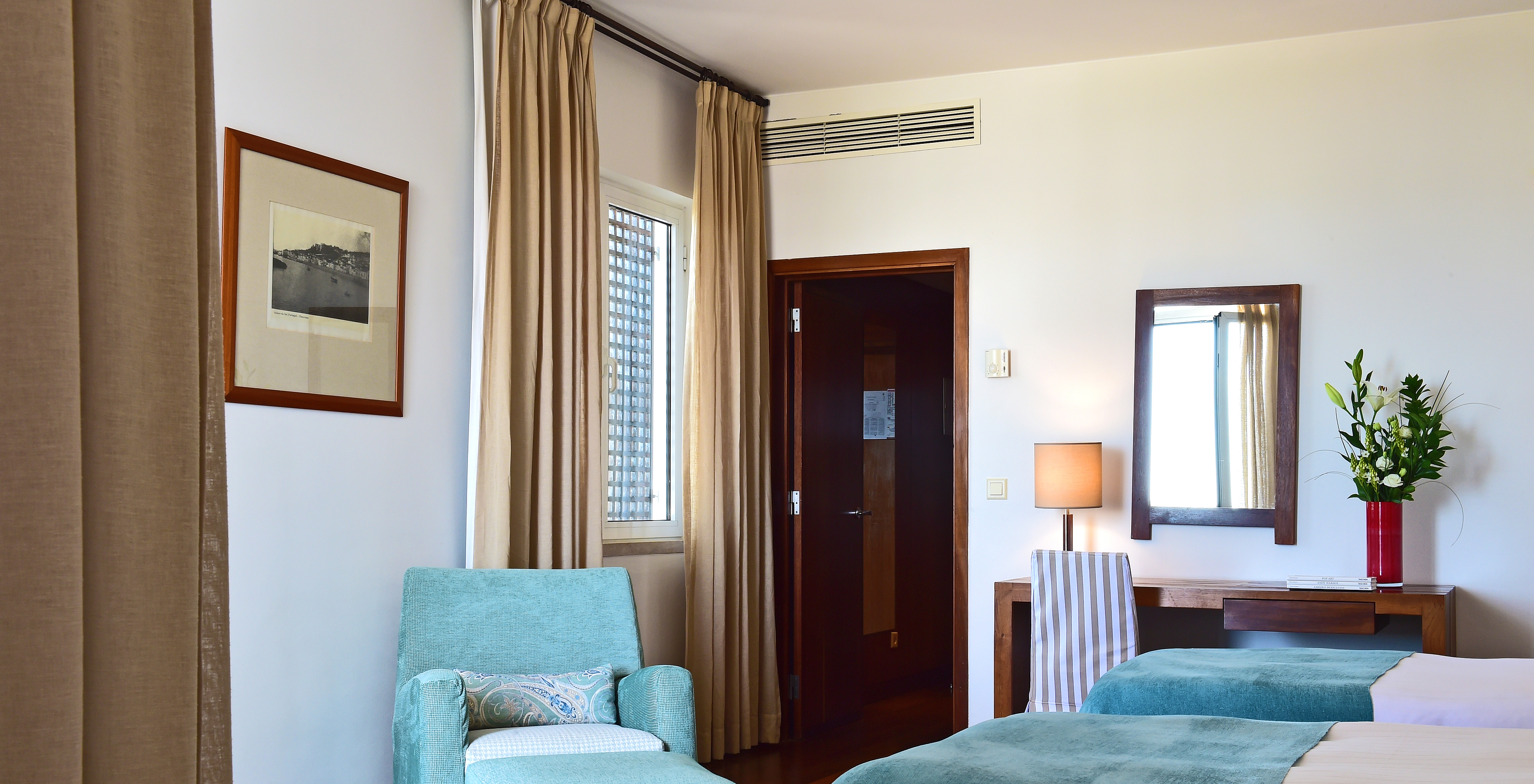 The Superior Family Room of the Pousada Castelo Alcácer do Sal has two separate beds, with a blue blanket and an armchair