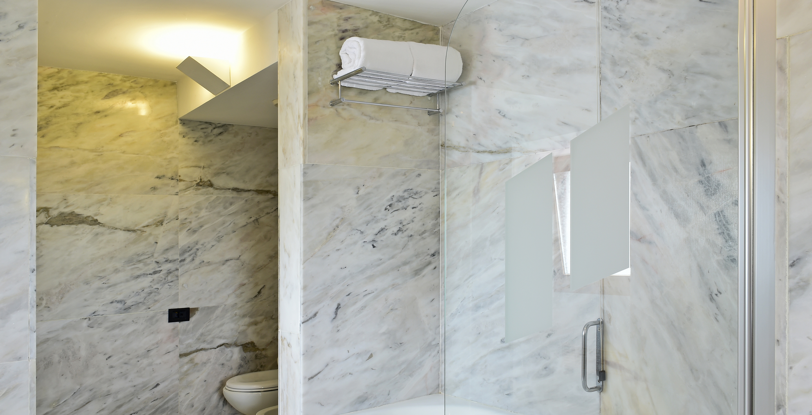 The Standard Suite of The Pousada Convento Arraiolos has a light marble bathroom with a bathtub, toilet, and bidet