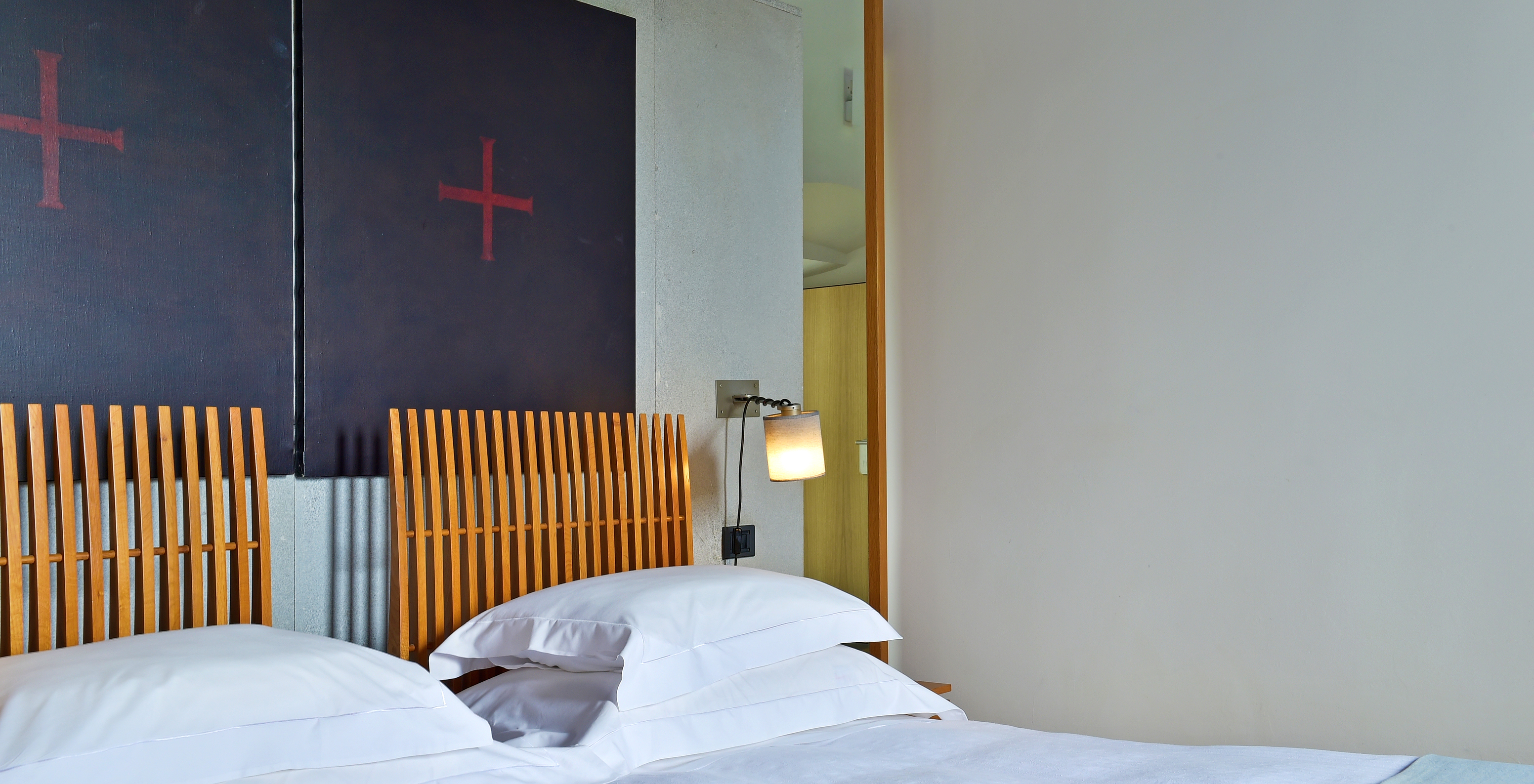 The Standard Suite of The Pousada Convento Arraiolos has two single beds with a wooden headboard and pictures with a cross