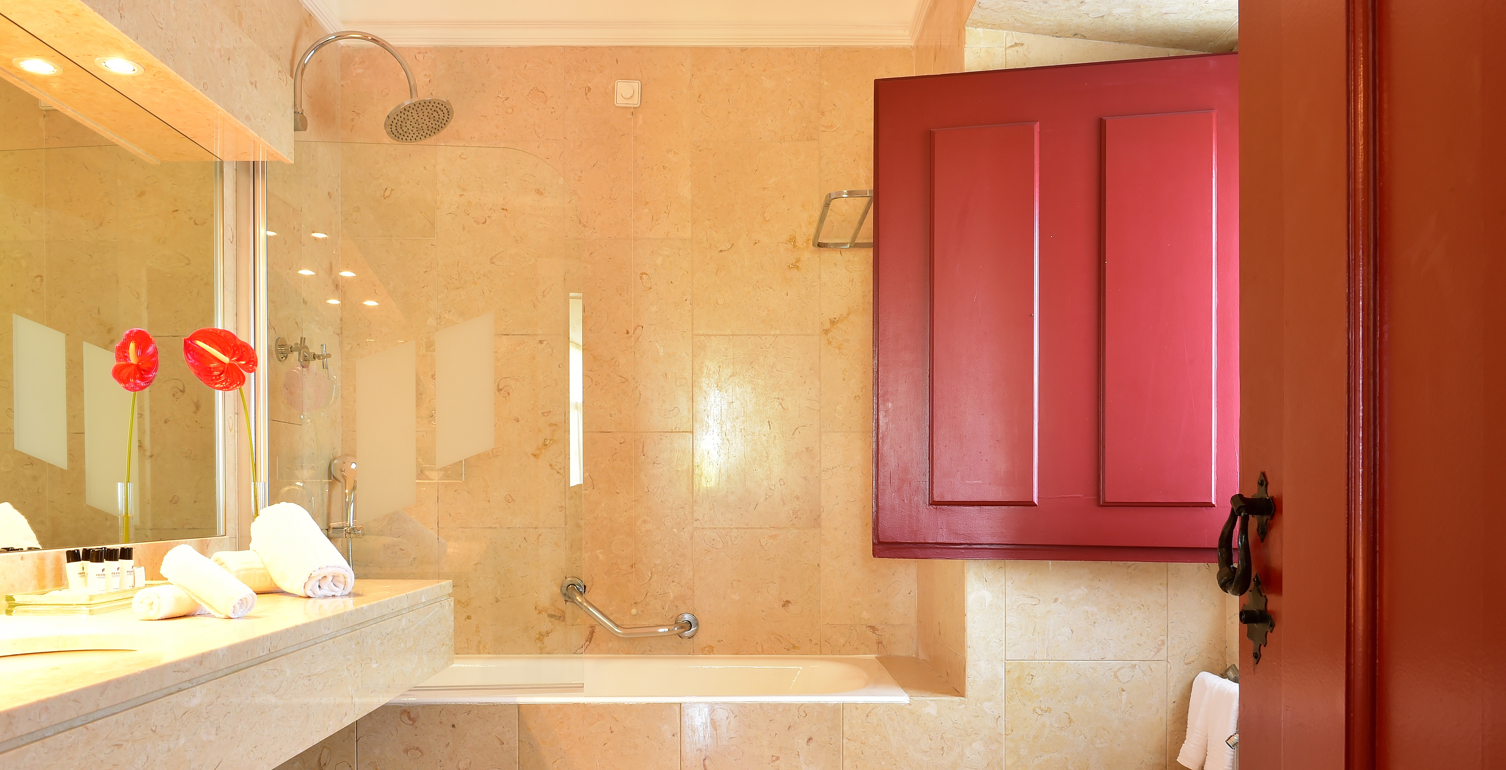 The Junior Suite of The Pousada Convento Beja has a bathtub with a shower and a decorative flower by the sink