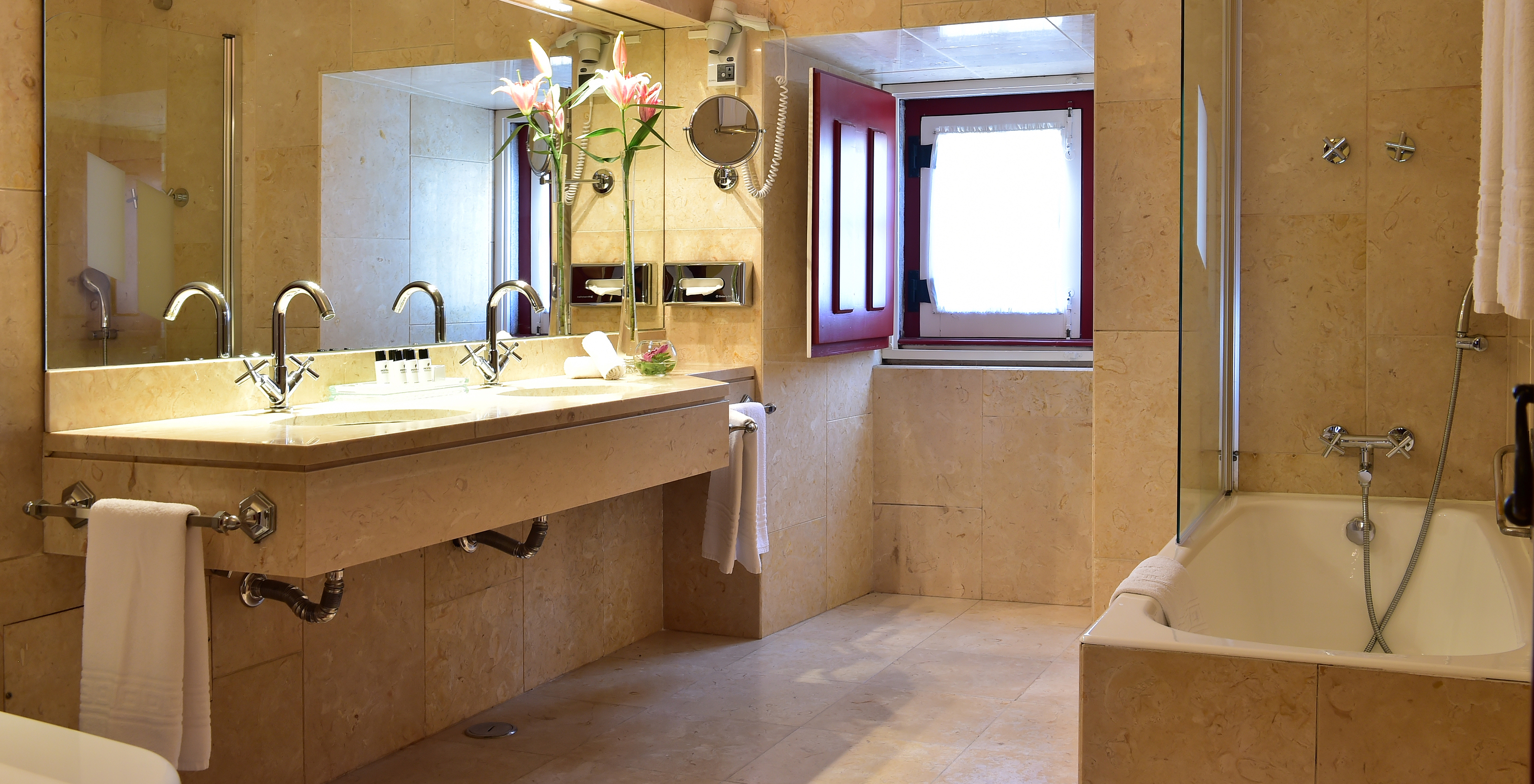 The Standard Suite of The Pousada Convento Beja has a spacious bathroom with a bathtub, large mirror, and two sinks