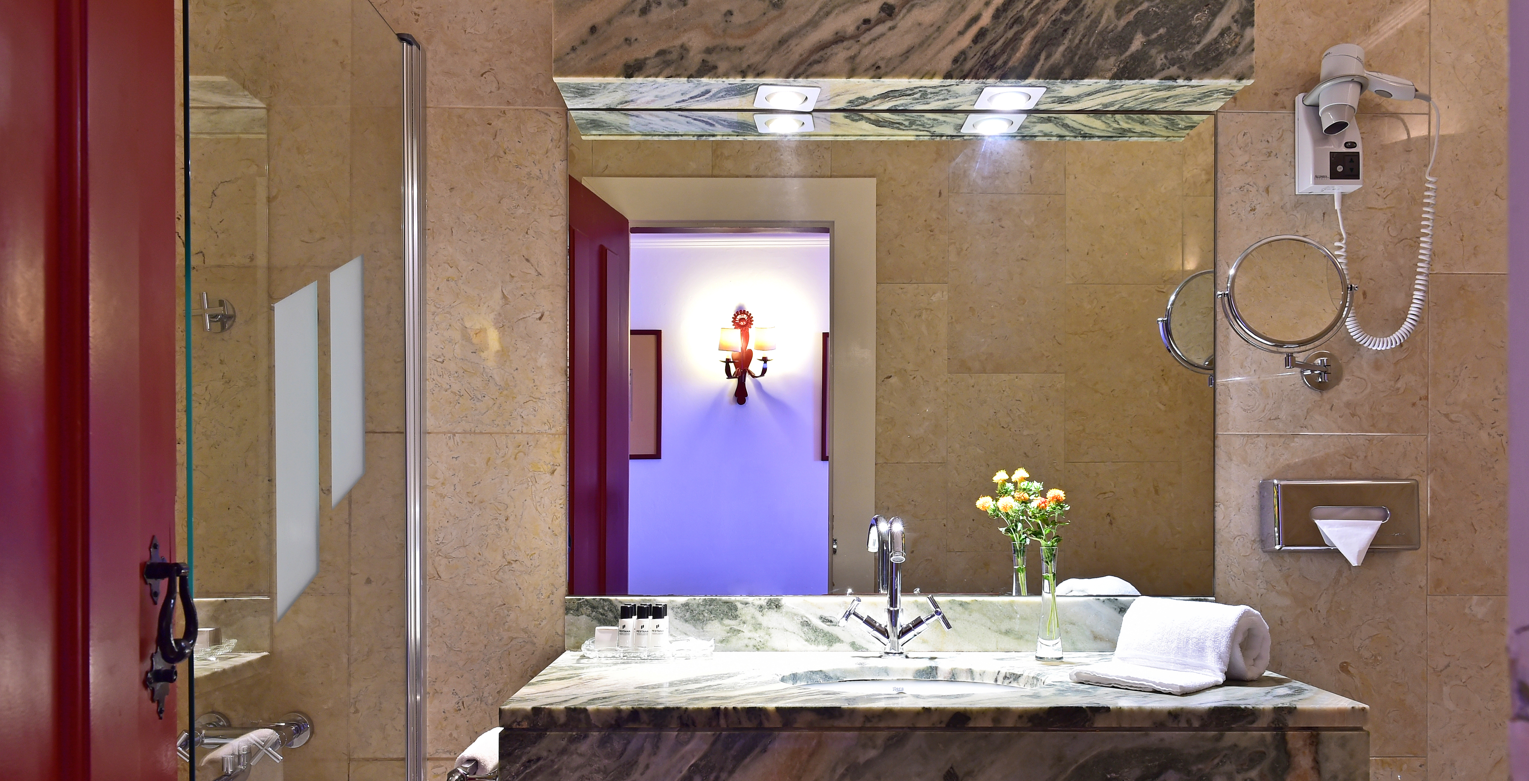 The Family Room of The Pousada Convento Beja has a counter with a sink, a large mirror, and a decorative flower