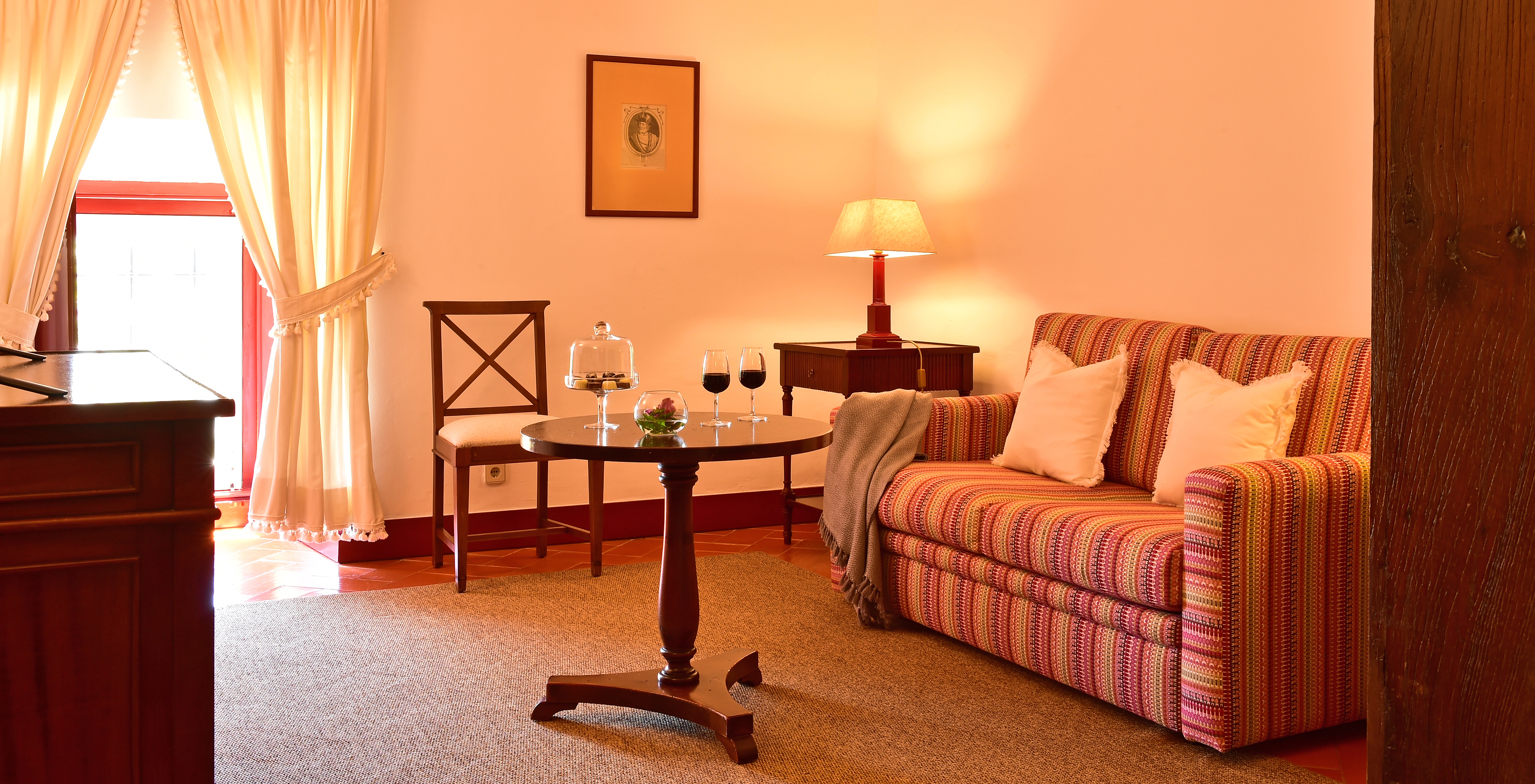 The Special Suite of The Pousada Convento Beja has a living room with a sofa, a side table, and two glasses of wine