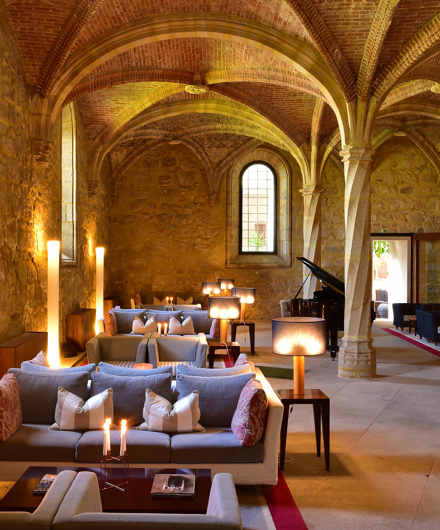 Hotel bar with sofas and tables for relaxing and socializing, and a black piano in a space with vaulted ceilings