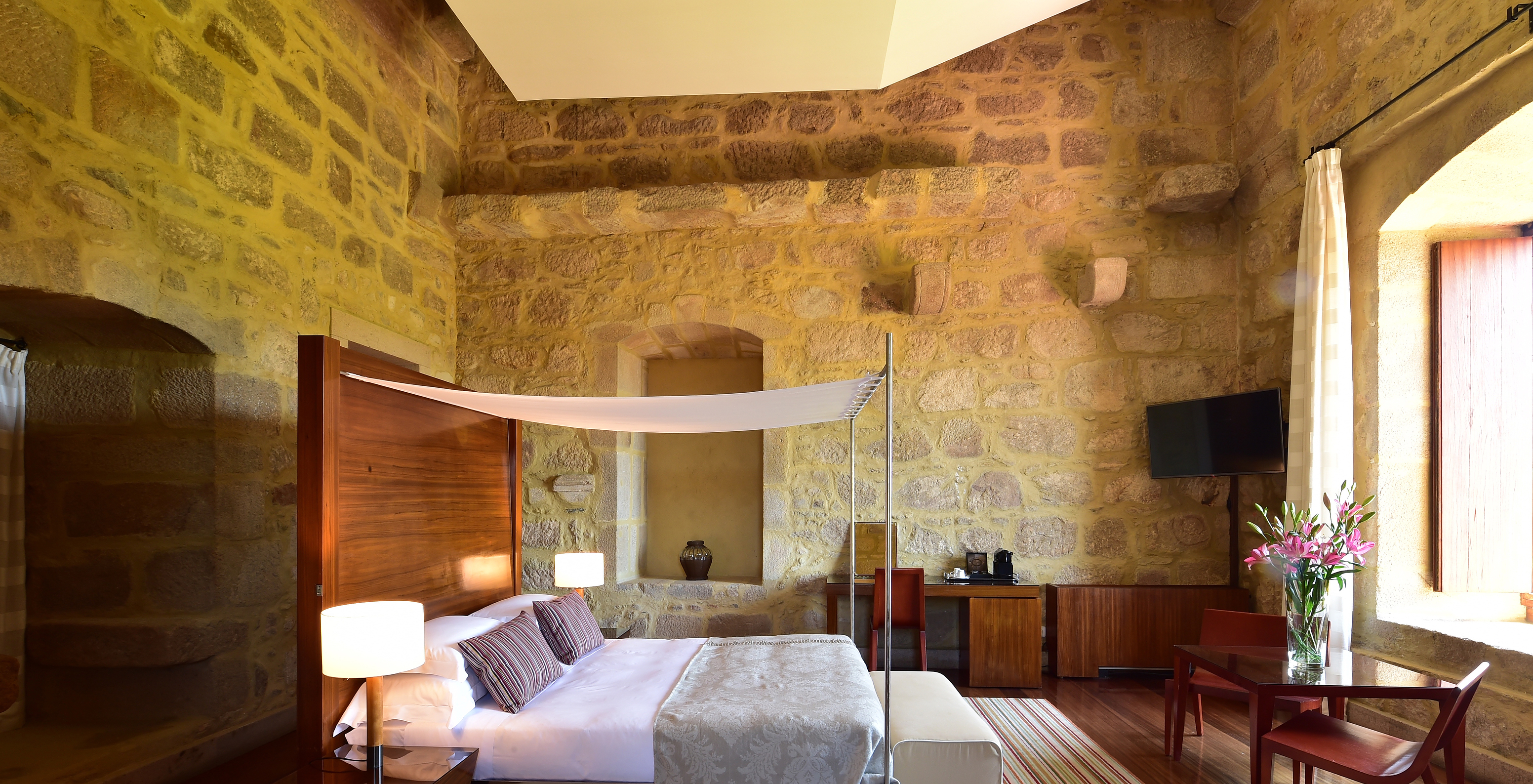 The Master Suite of The Pousada Mosteiro Crato is spacious with a four-poster double bed and also has a desk and a television