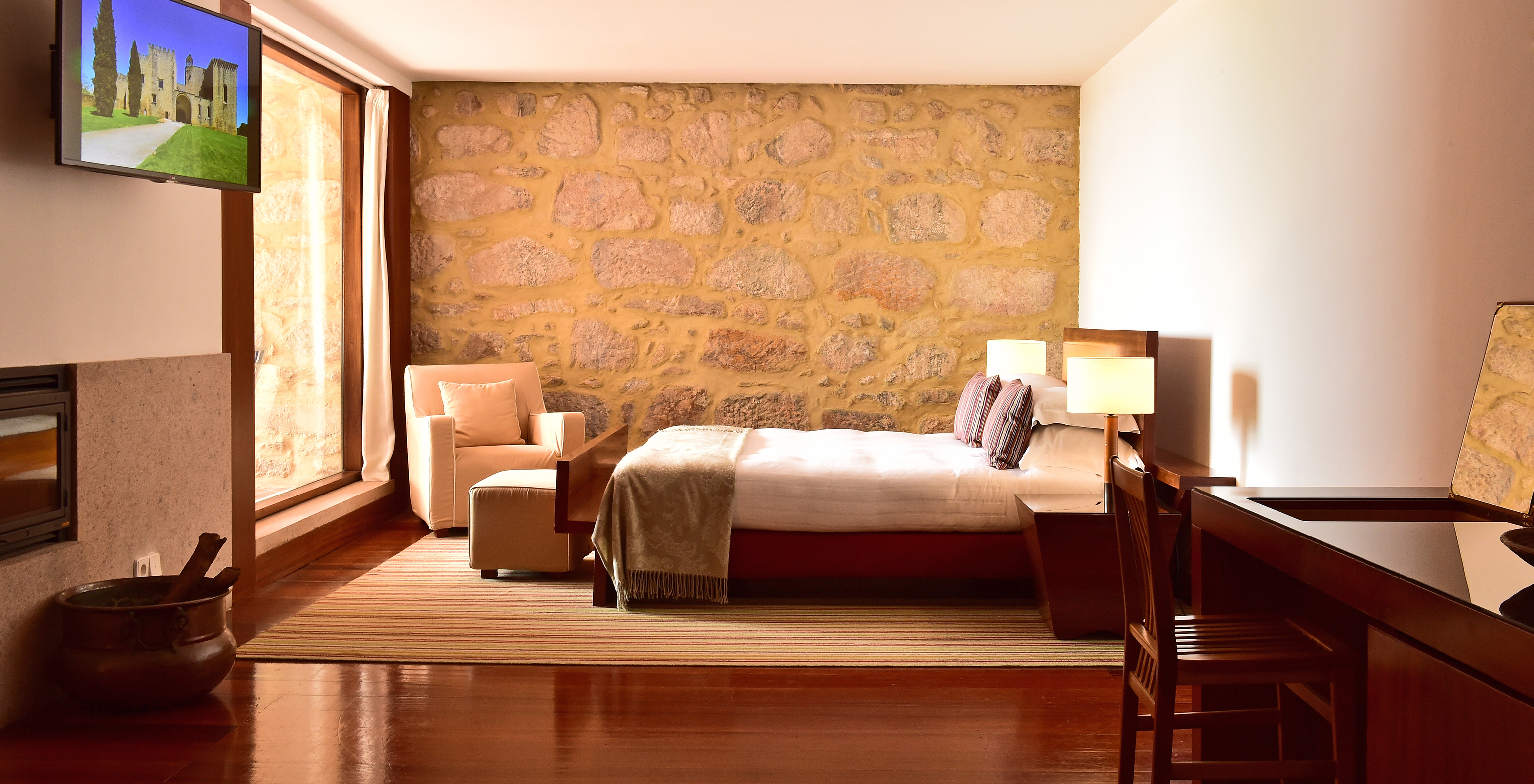 The Standard Suite of The Pousada Mosteiro Crato has a double bed with an armchair, TV, desk, and a small fireplace