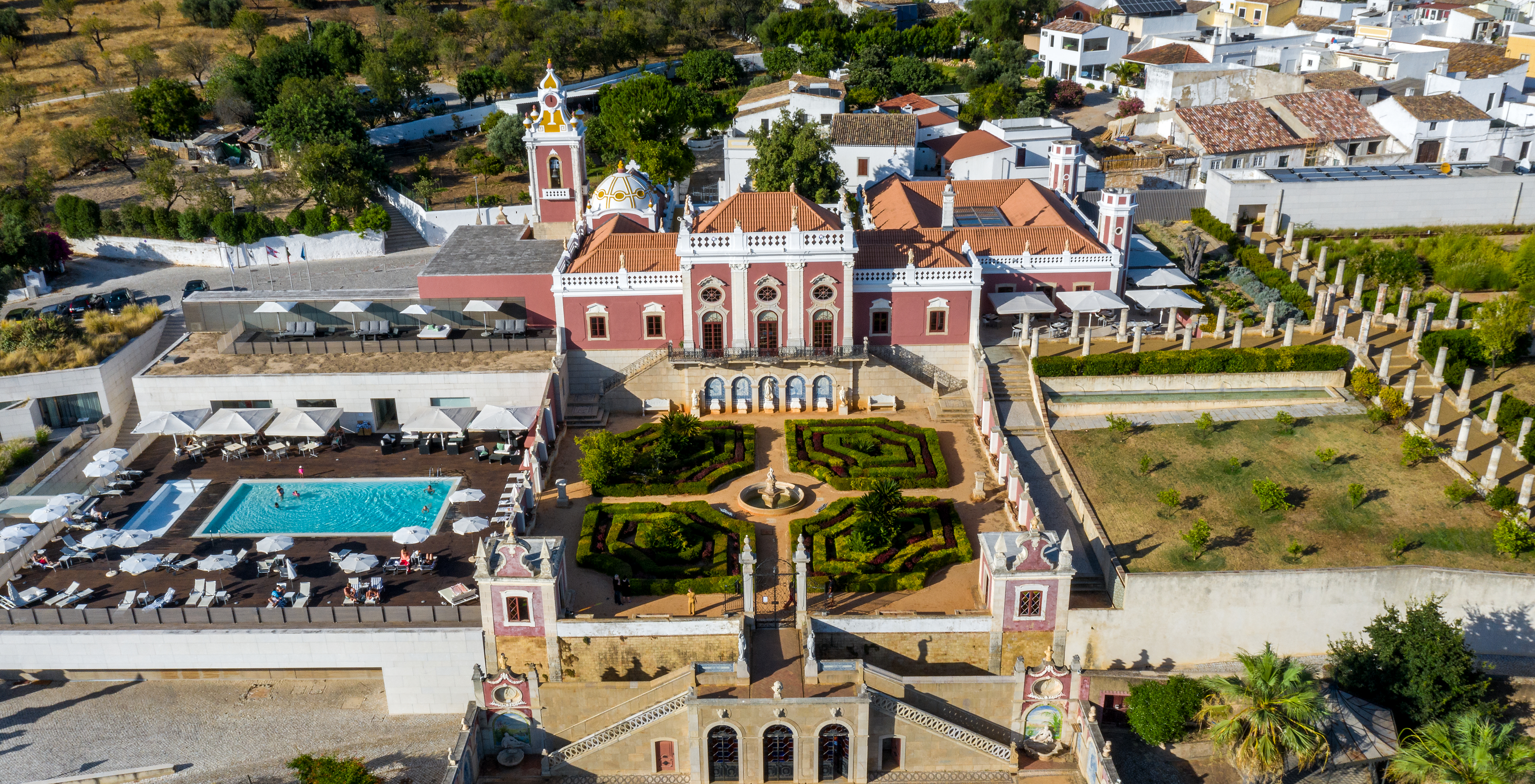 Aerial view of Pousada Palácio Estoi, a historic hotel in Faro, with manicured gardens, the old palace, and outdoor pool