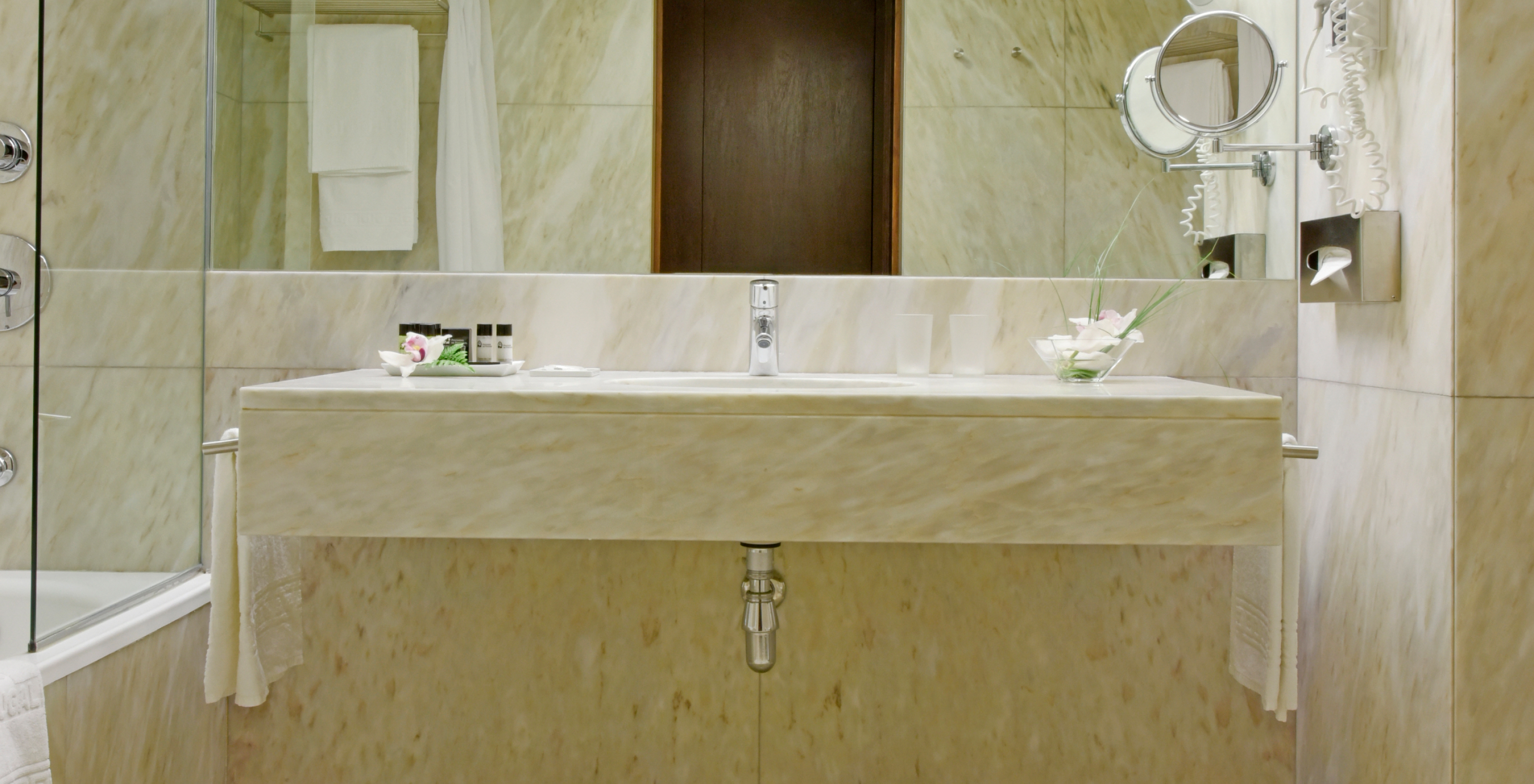 The Classic Room of The Pousada Palácio Estoi has a marble bathroom with a sink with a mirror and hairdryer