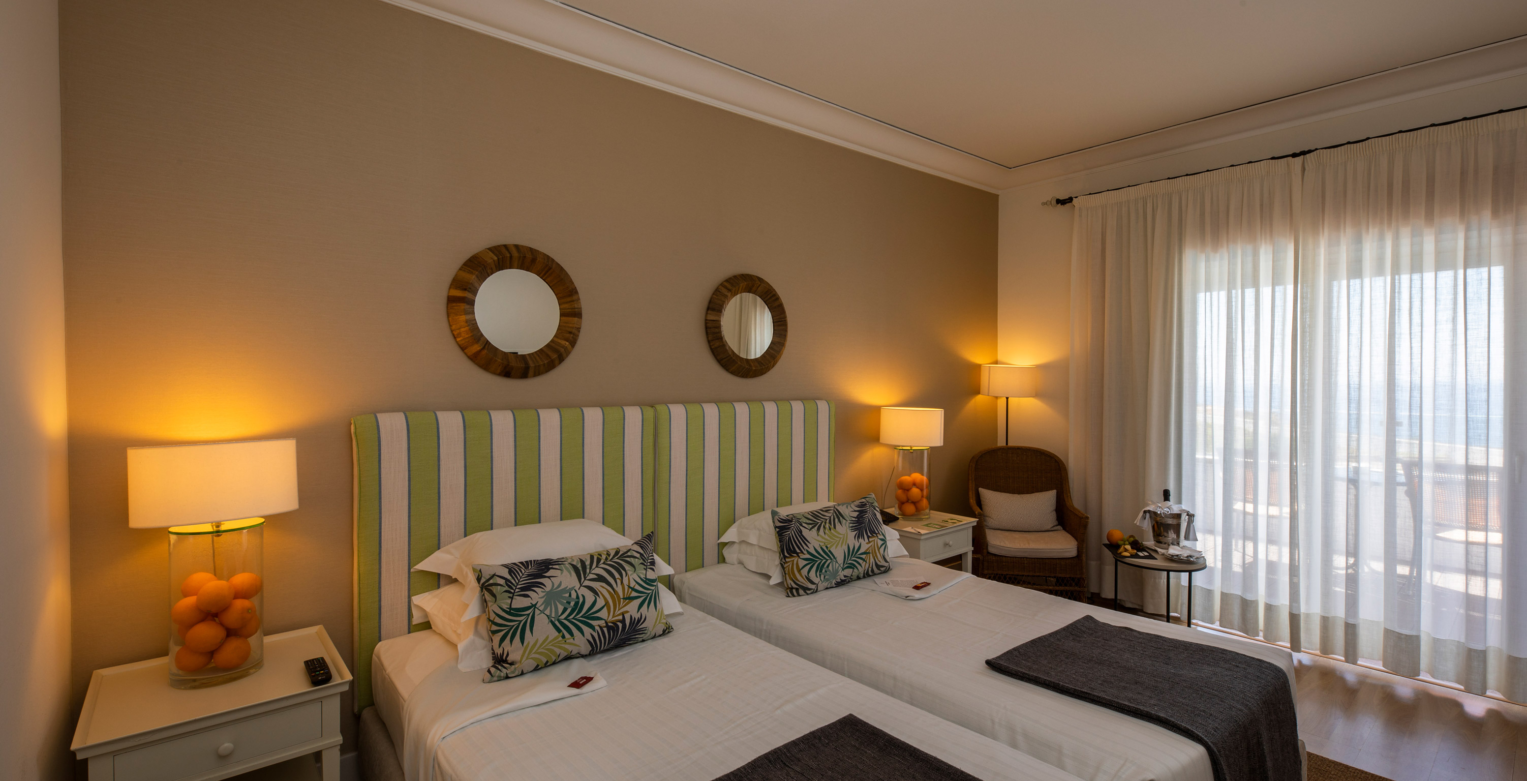 The Classic Room of Pousada Sagres has two beds with striped headboards, two round mirrors, and a balcony