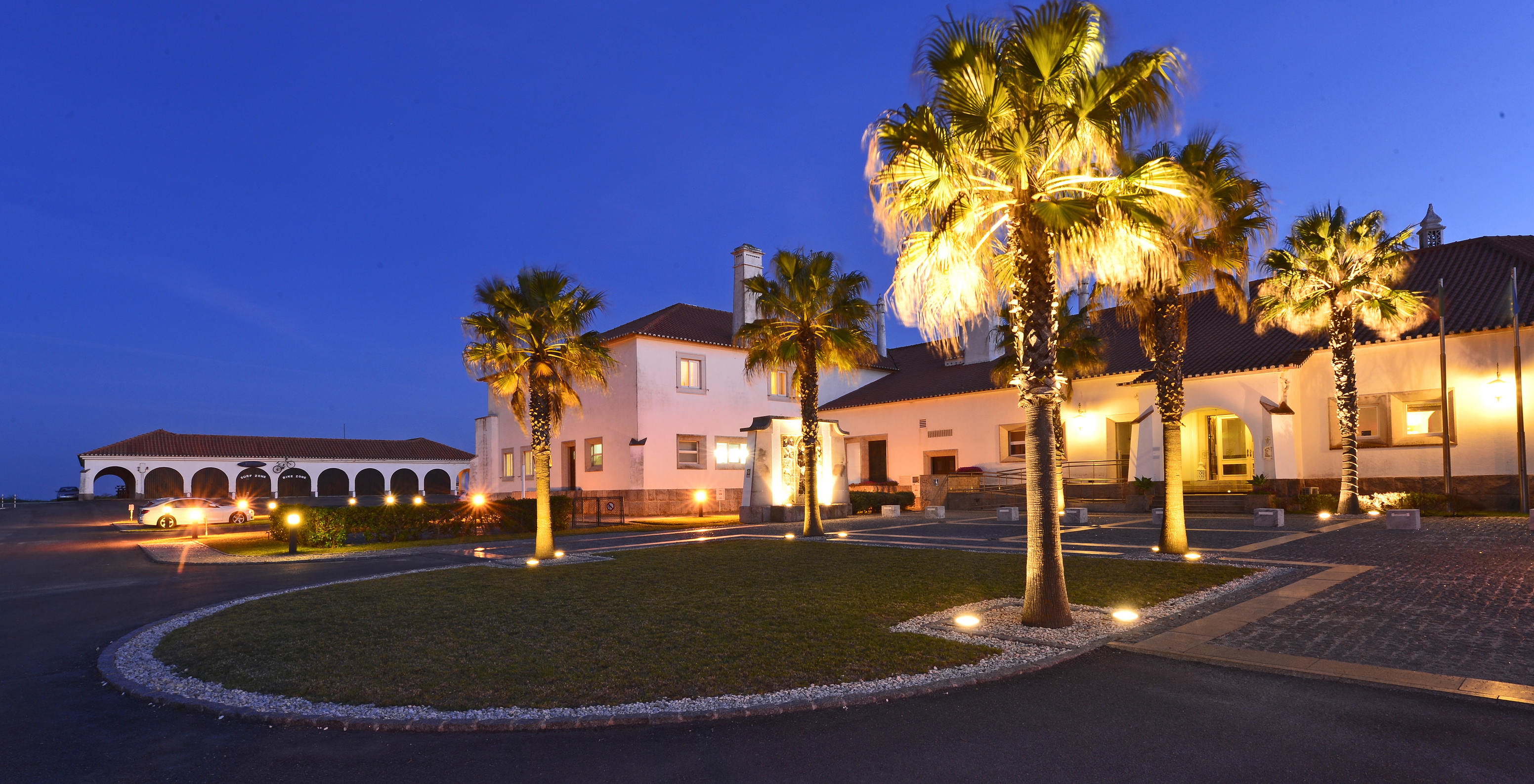 Exterior of Pousada Sagres at night, illuminated with palm trees and lamps