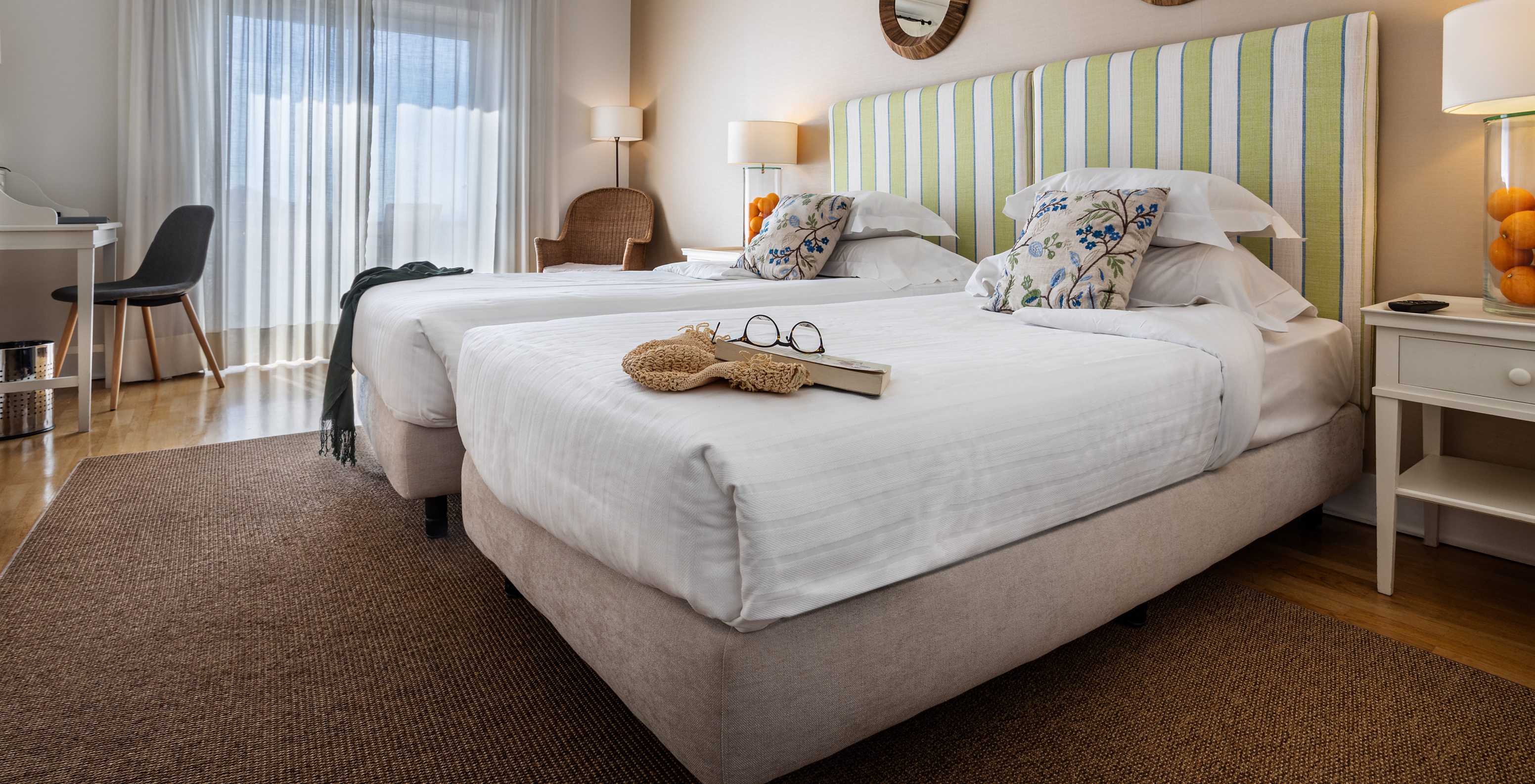 The Classic Room of Pousada Sagres has two beds with striped headboards, two mirrors, a balcony, and a desk