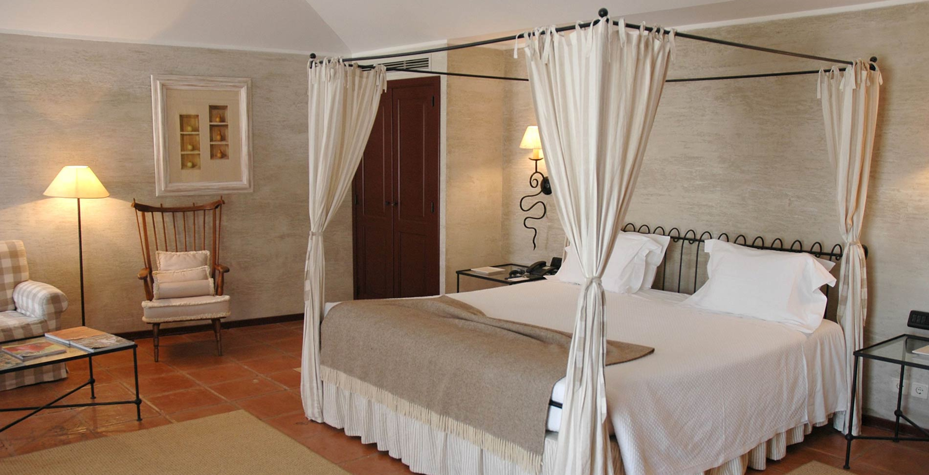 The Deluxe Room of The Pousada Convento de Belmonte has a double bed with a brown blanket and two pillows