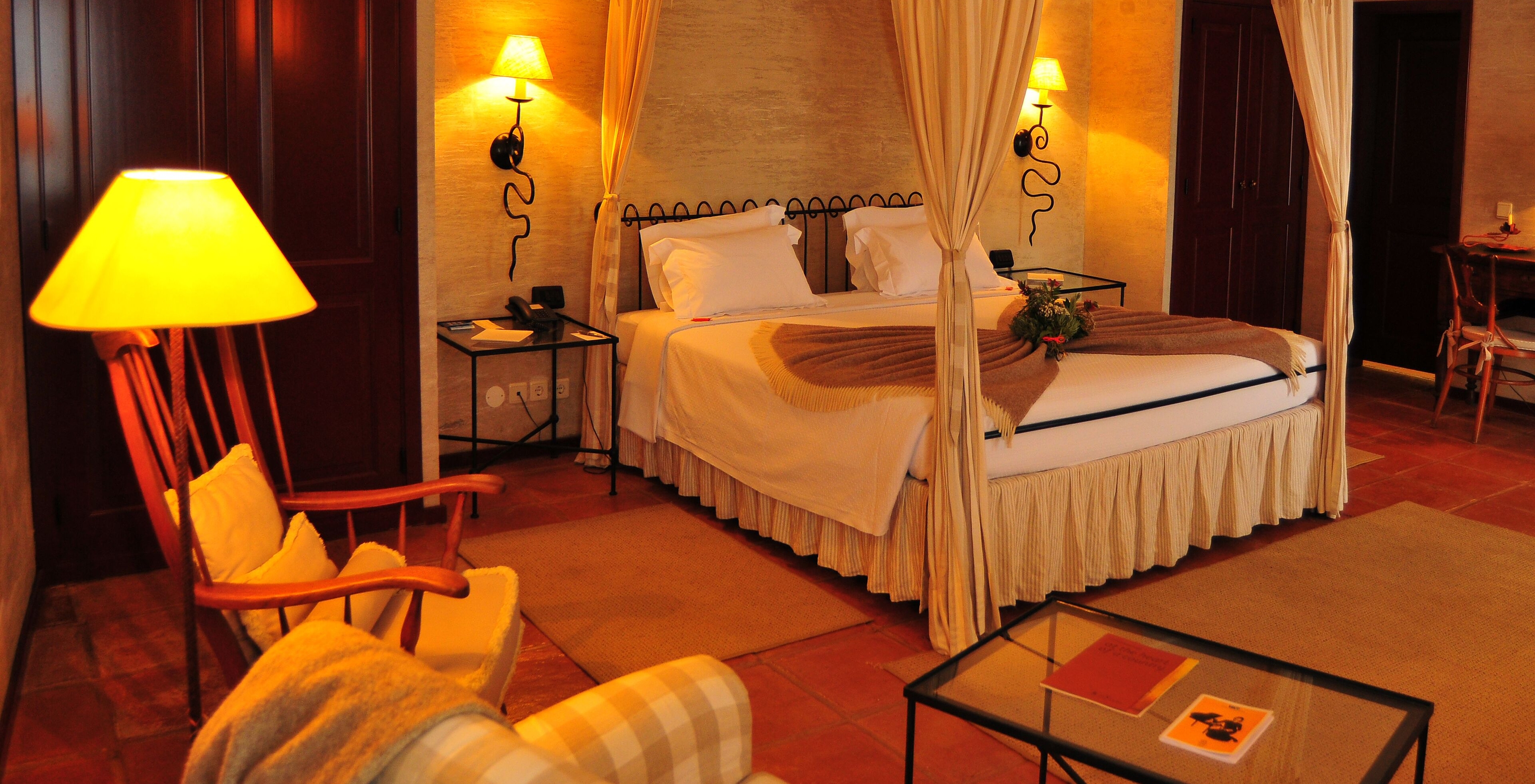 The Deluxe Room of The Pousada Convento de Belmonte has a double bed with two bedside tables and three lamps