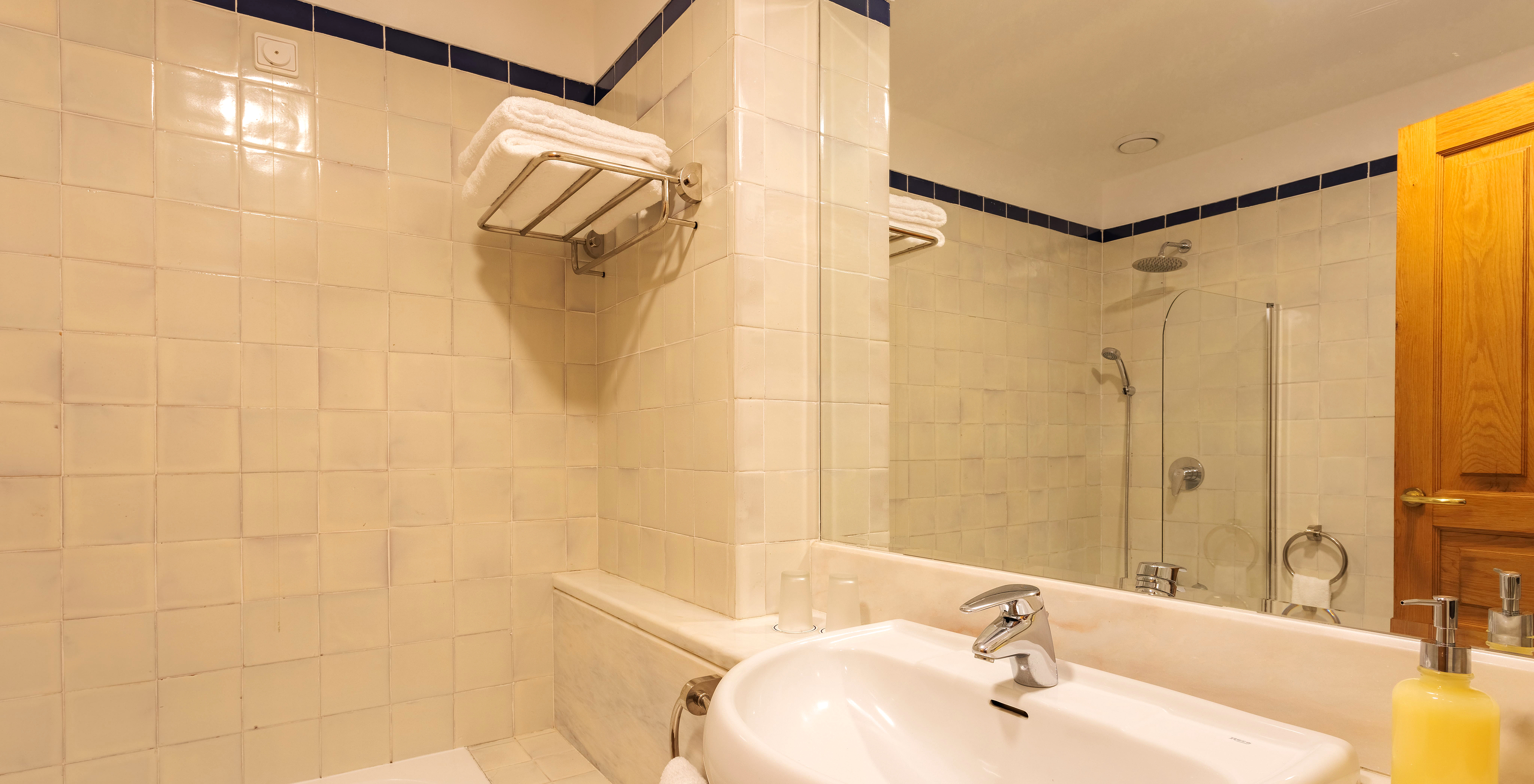 The Classic Room of The Pousada Ourém has a sink with a large mirror and a bathtub with a shower