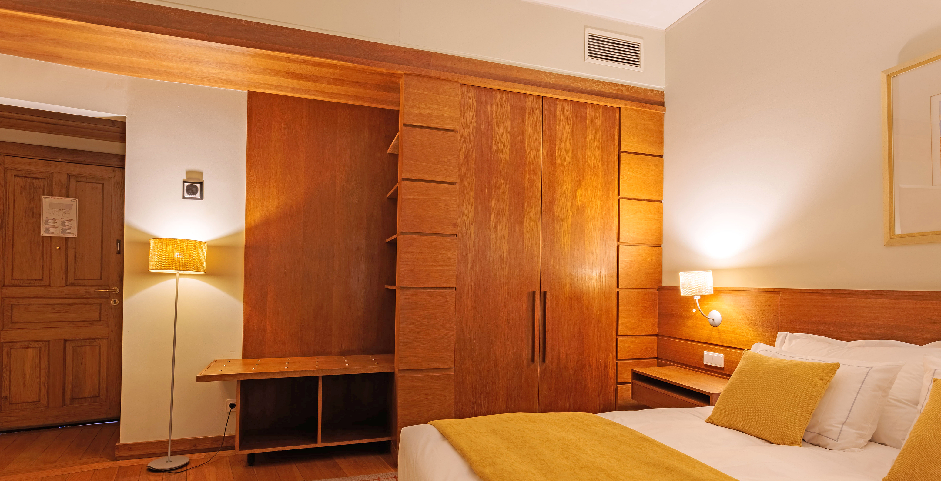 The Classic Room of The Pousada Ourém features a double bed with a yellow bedspread and a wardrobe beside it