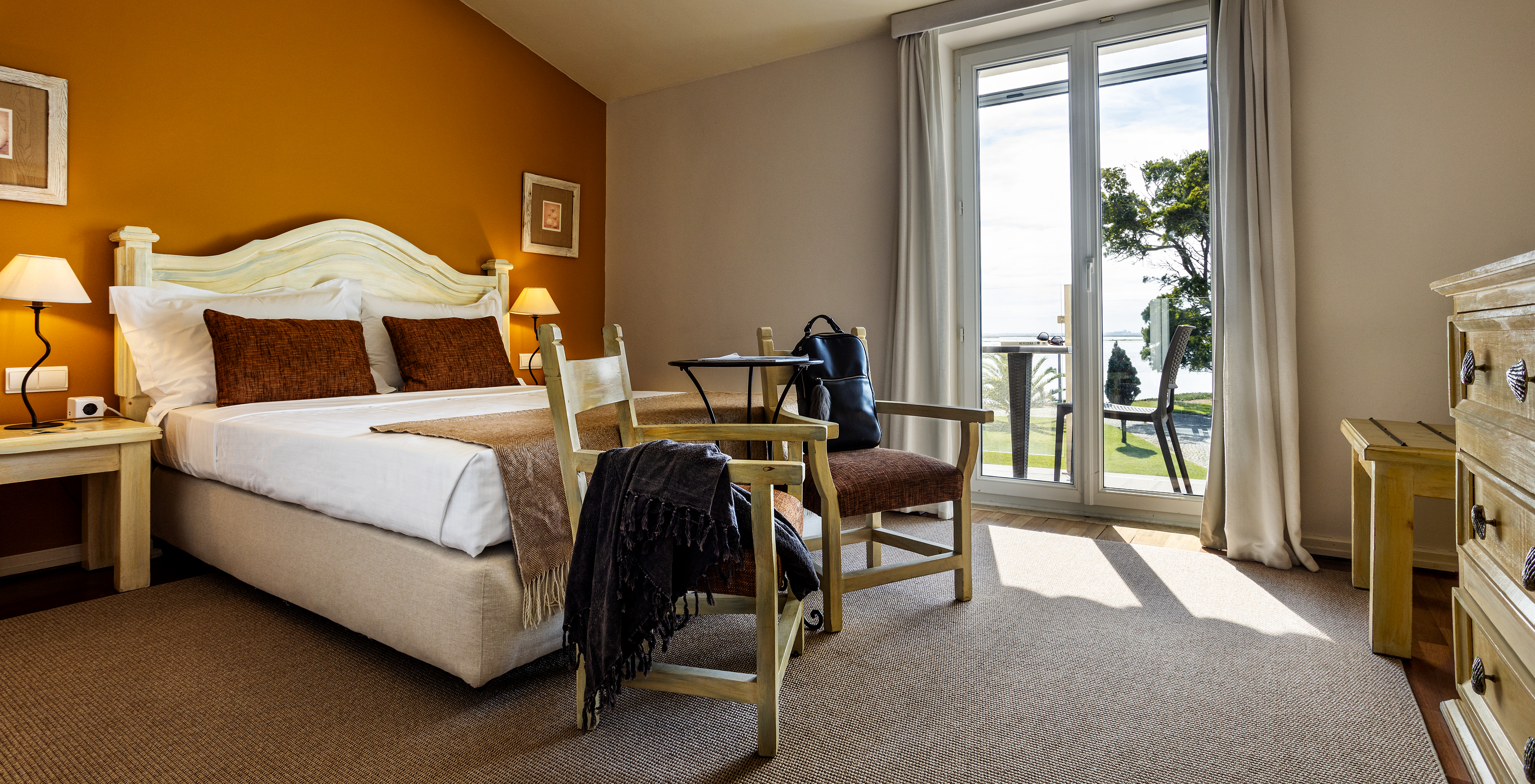 The Classic Room of The Ria Inn - Aveiro has a double bed, two chairs, and a balcony with a view of the ria