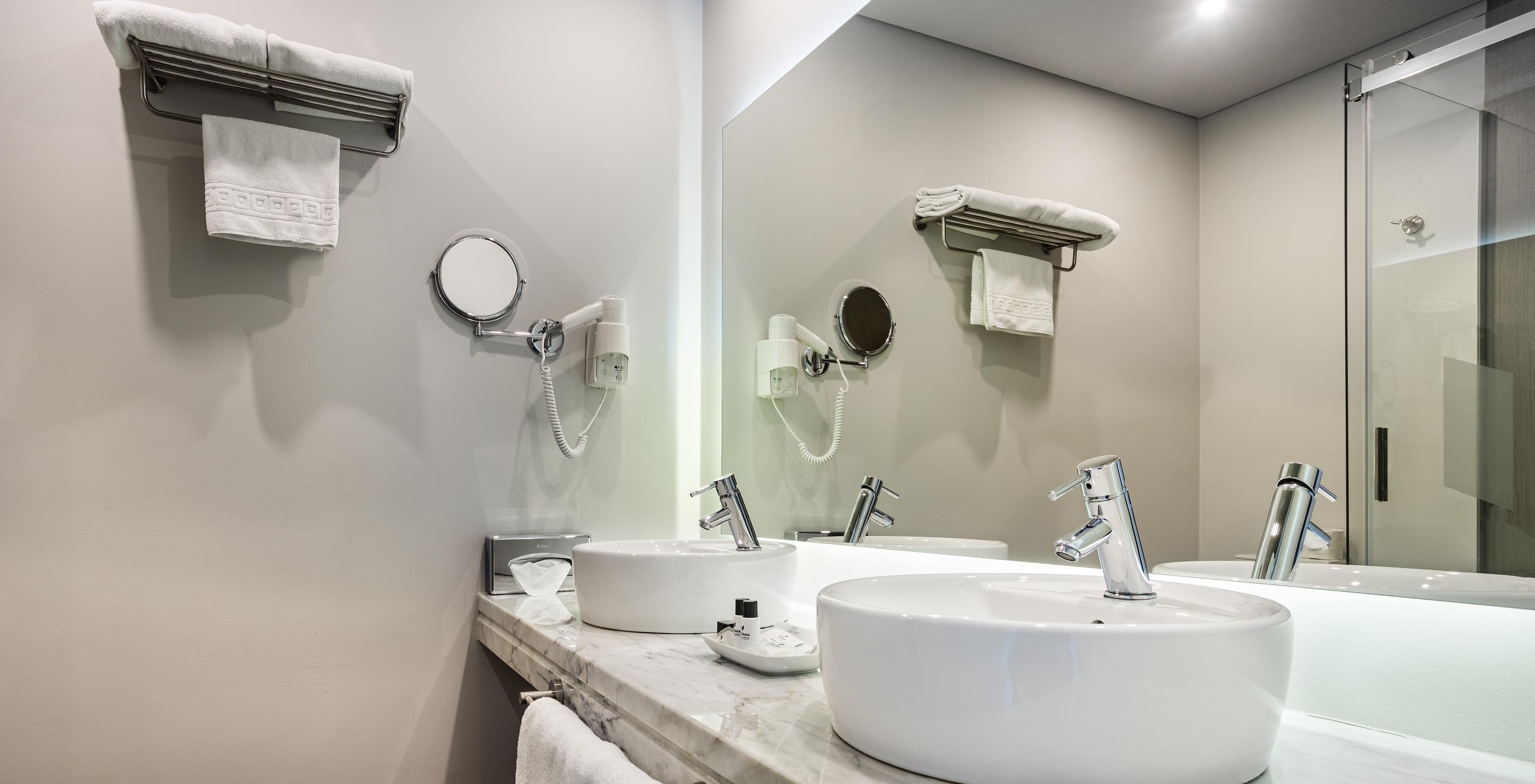 The Premium Large Family Room of The Ria Inn - Aveiro has two sinks, a large mirror, towels, and a hairdryer