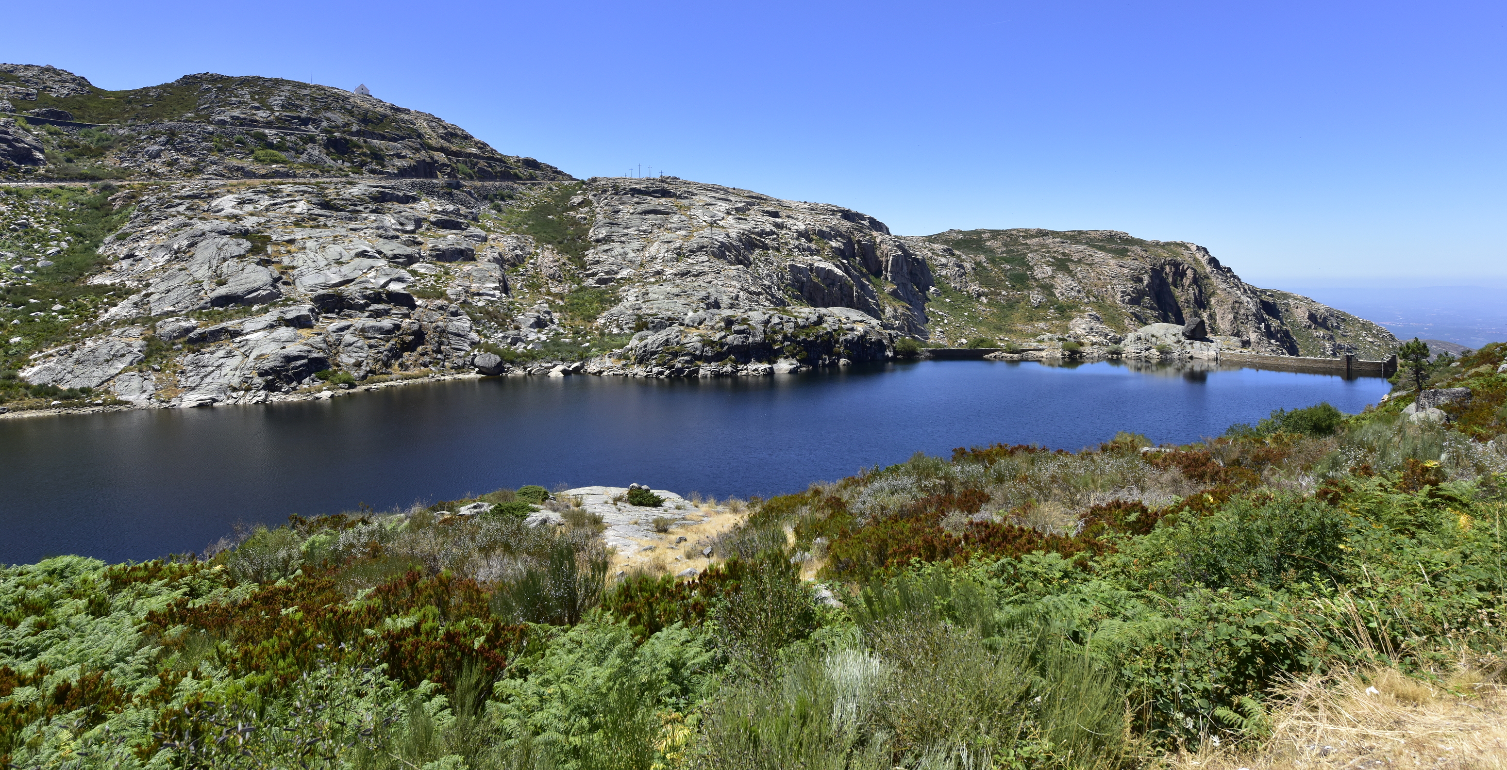 Lake in Serra da Estrela with calm waters reflecting the blue sky and mountains