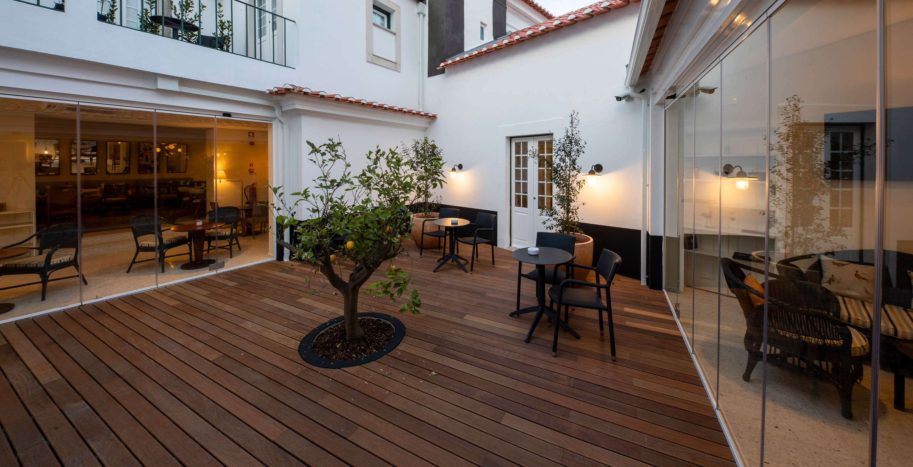 Outdoor patio at Pousada Vila Óbidos, Bed and Breakfast in Óbidos, with two tables and a tangerine tree