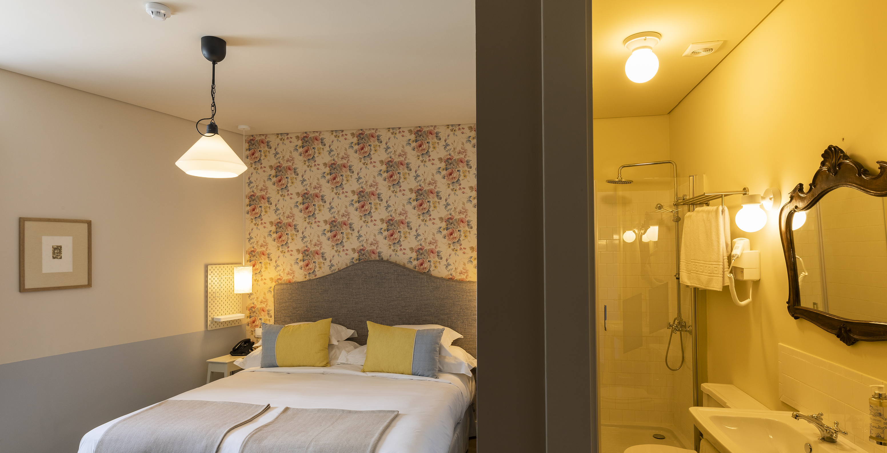 The Classic Room of The Pousada Vila Óbidos has a double bed, floral wallpaper, and a bathroom with a shower and toilet